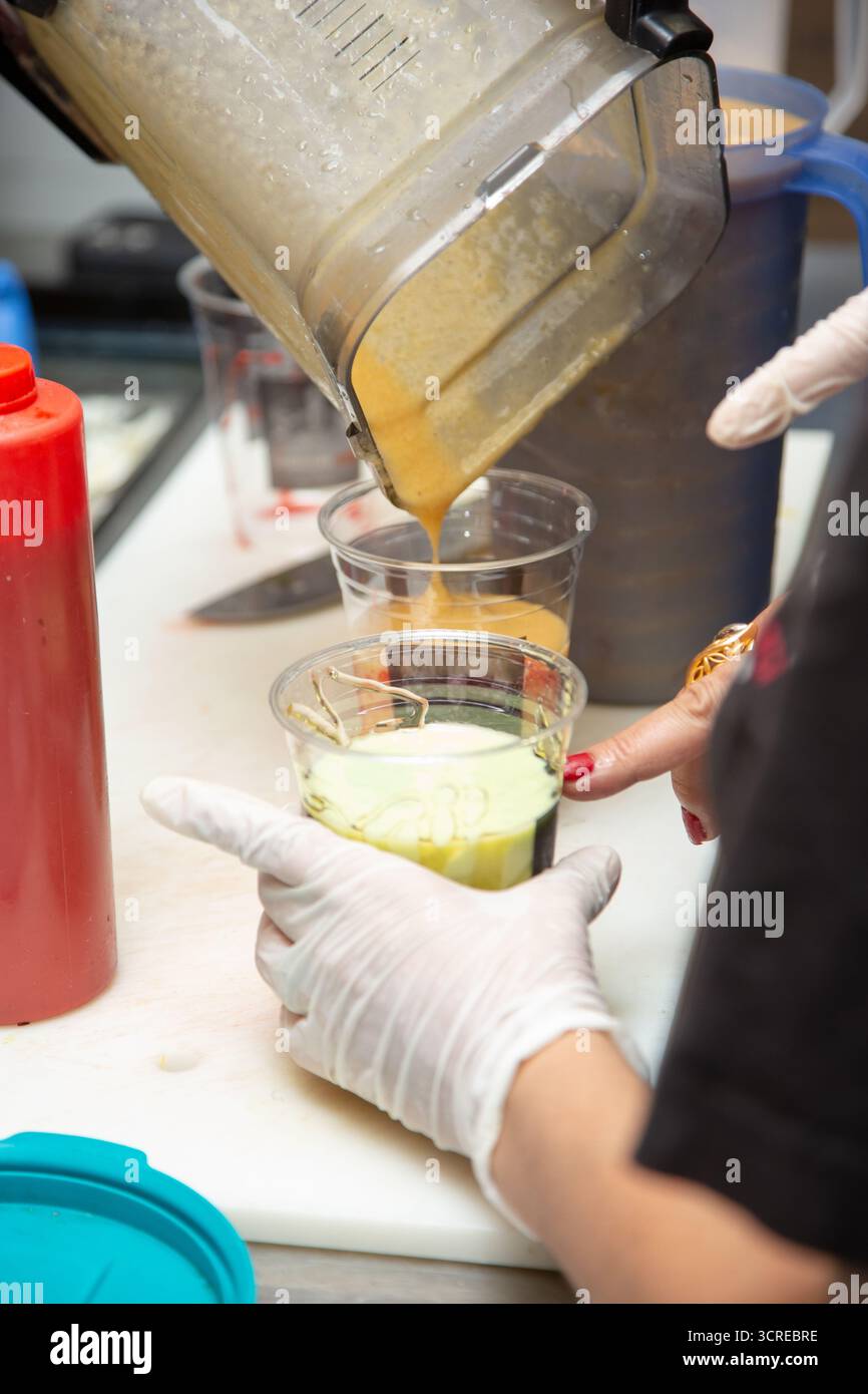 Vista dei lavoratori che preparano bevande miste alla frutta presso la stazione degli ingredienti di un ristorante locale. Foto Stock