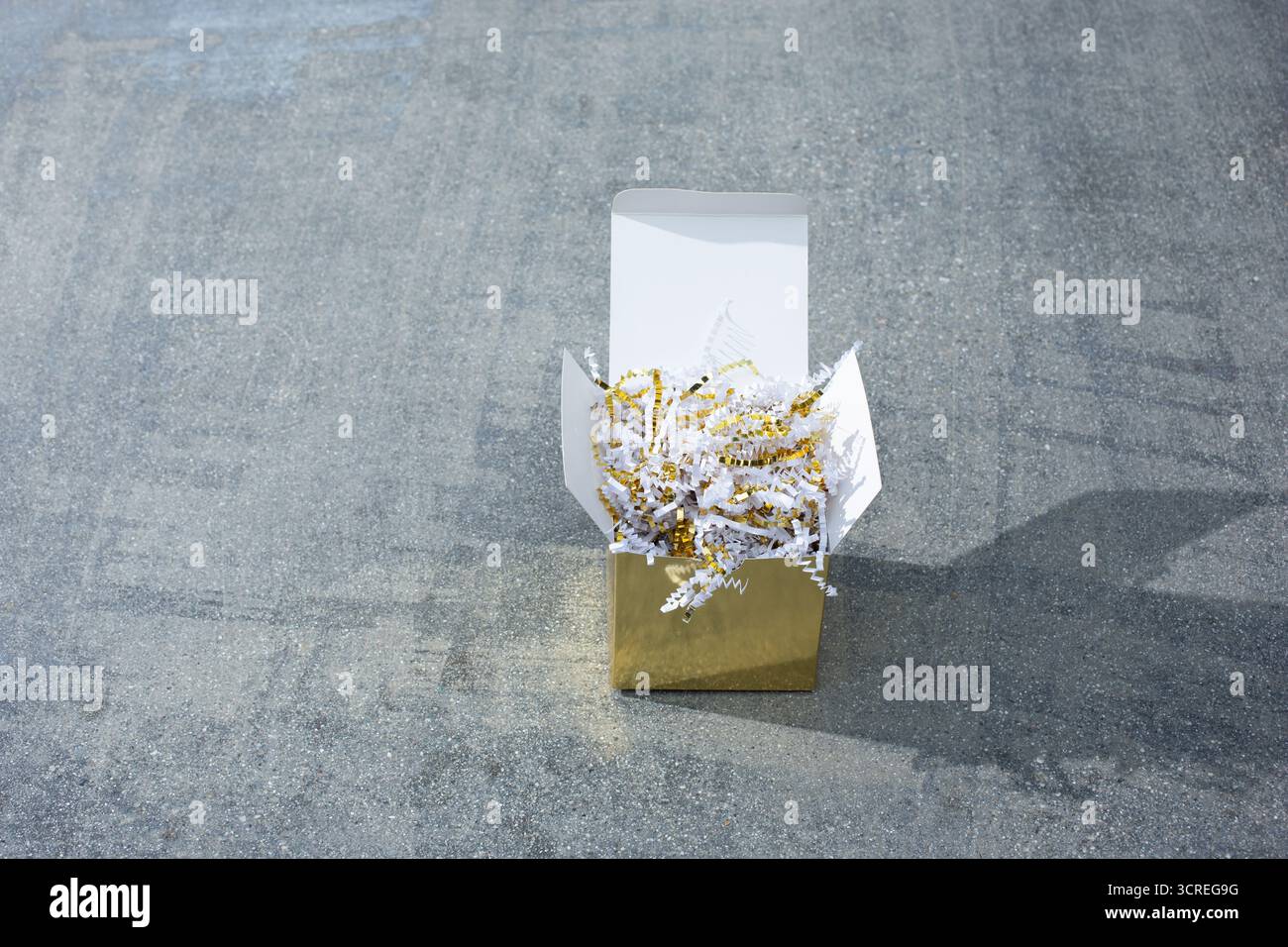 Una vista di una confezione regalo con imbottitura in carta con taglio increspato oro e bianco. Foto Stock