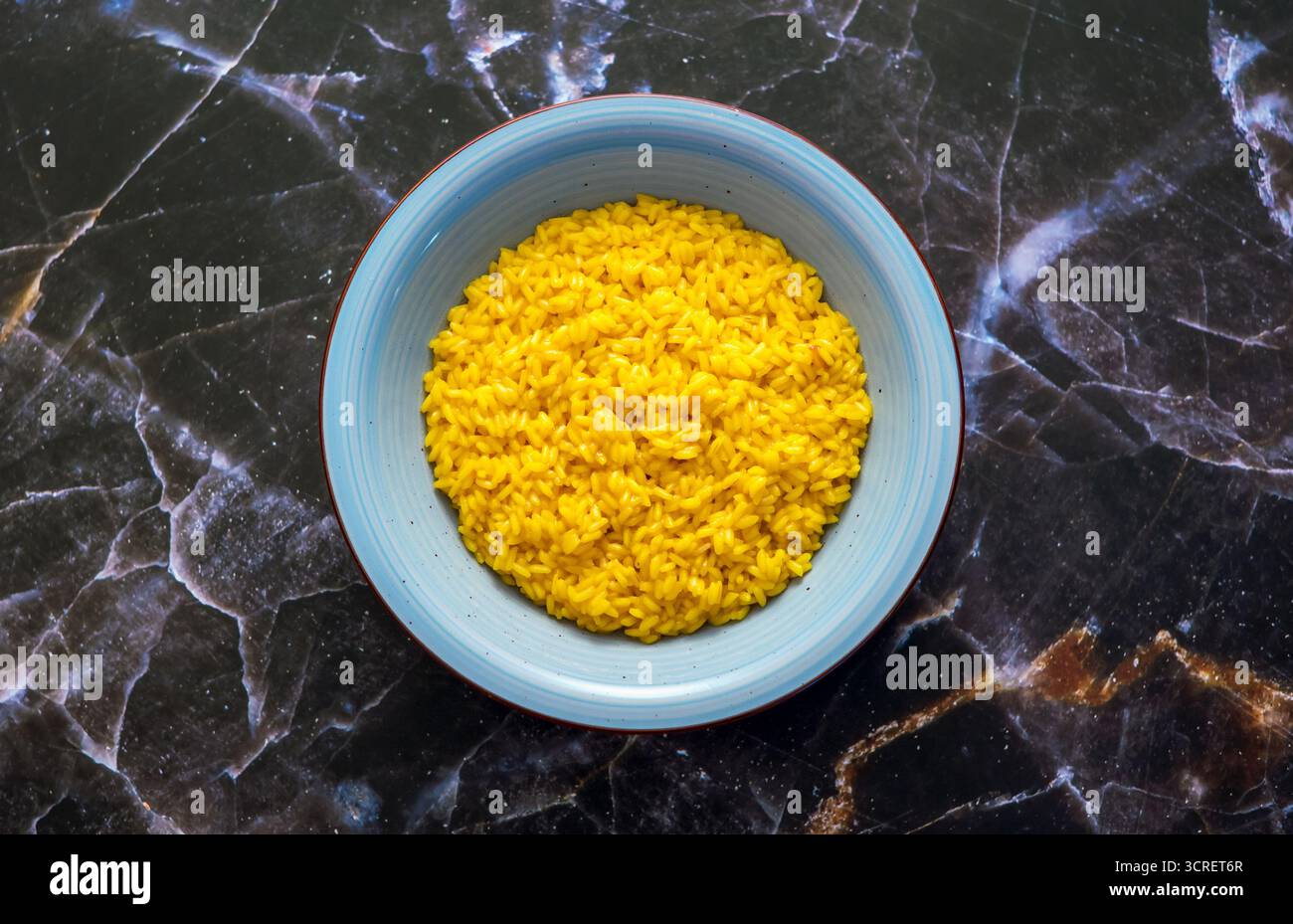 Tradizionale risotto italiano allo zafferano, una specialità lombarda, che serve un pasto delizioso Foto Stock