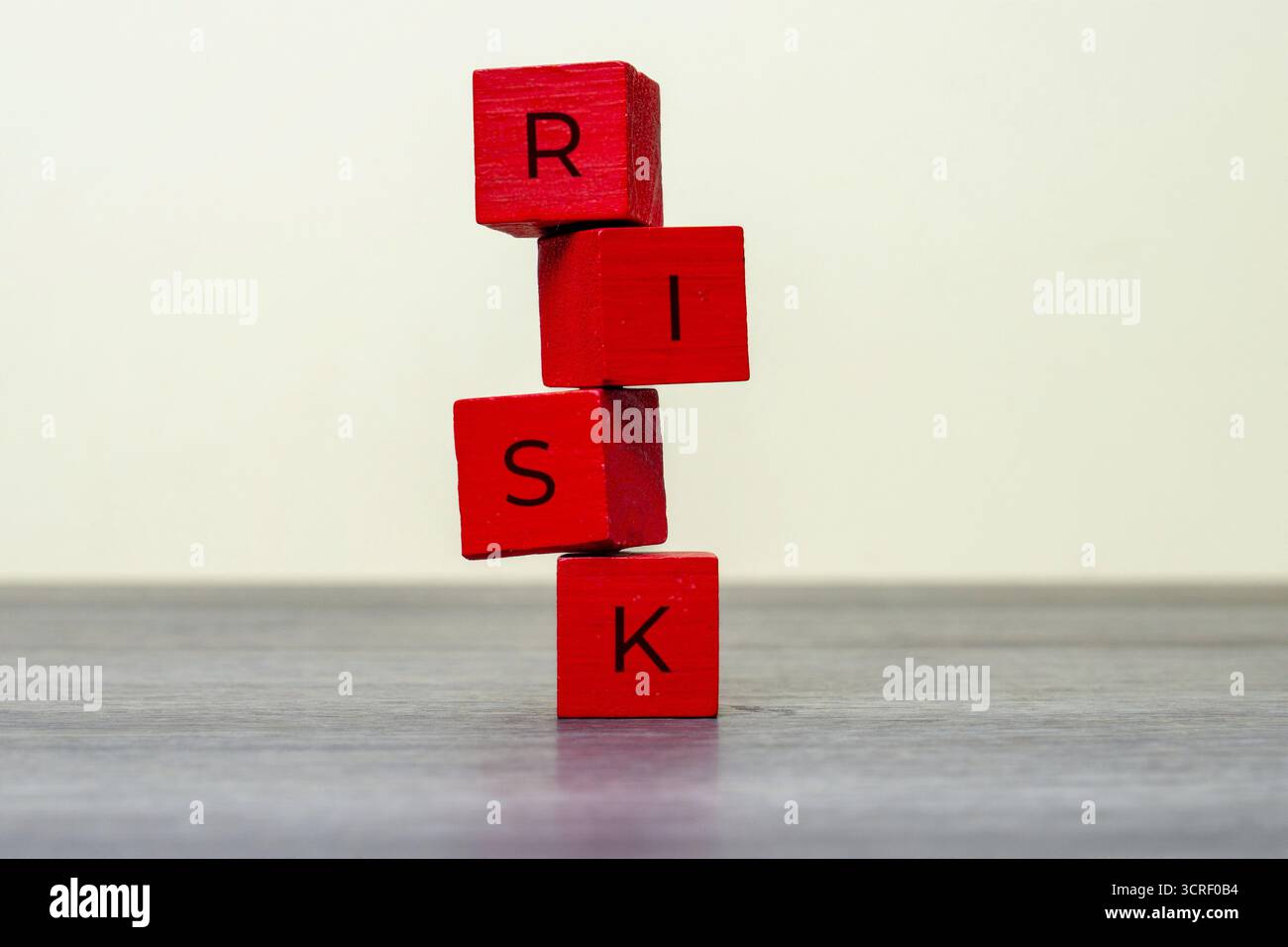 Blocchi di legno rossi impilati precariamente con la parola RISCHIO. Pericolo, incertezza o situazione di rischio elevato nel concetto di business o finanza. Foto Stock