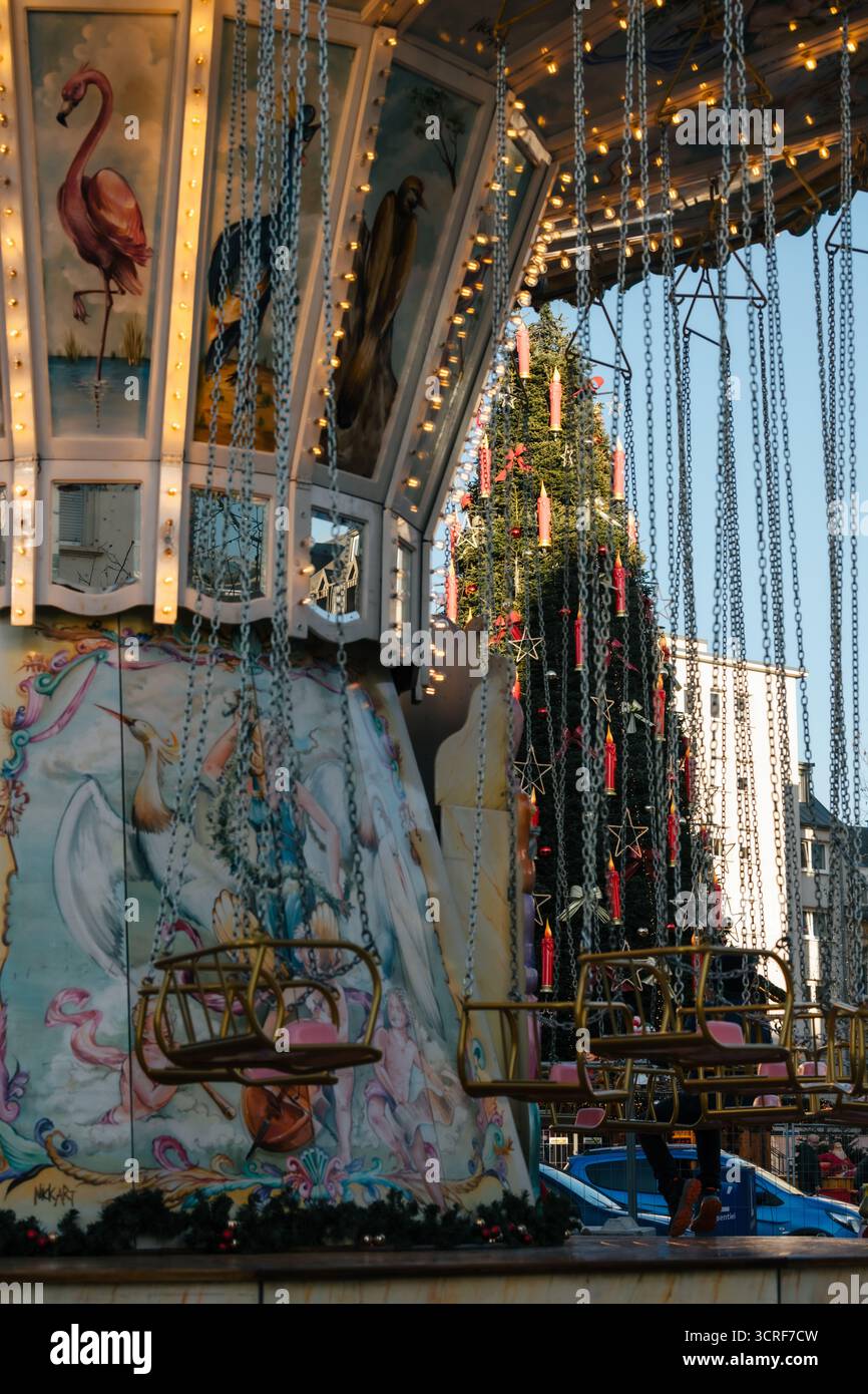 La vista di una giostra animata adornata da luci festose e stravaganti opere d'arte si snoda su uno sfondo di cieli limpidi, la città di Lussemburgo, Lussemburgo. Foto Stock