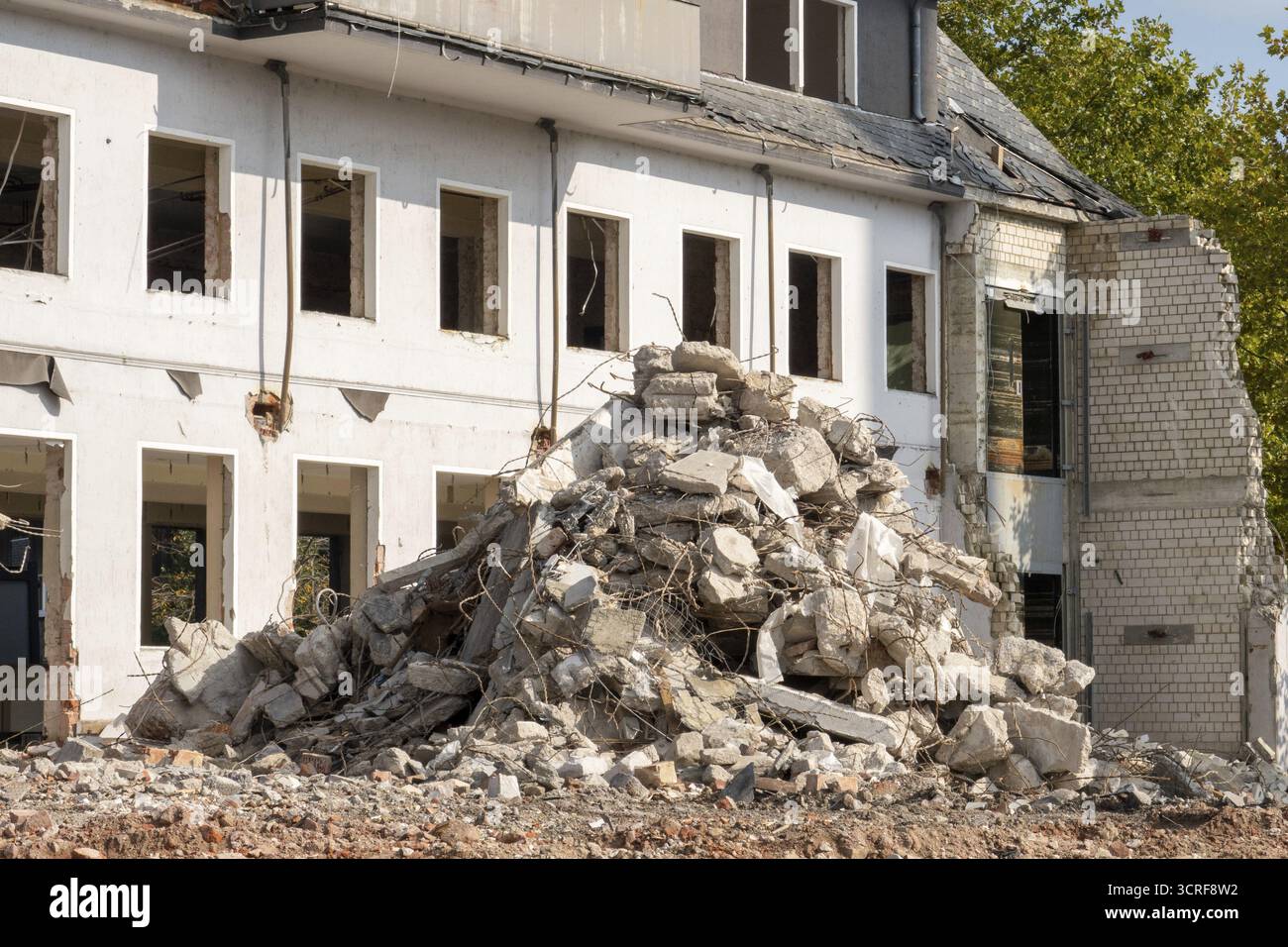 Macerie di cemento e mattoni che si accumulano di fronte a un edificio parzialmente demolito Foto Stock