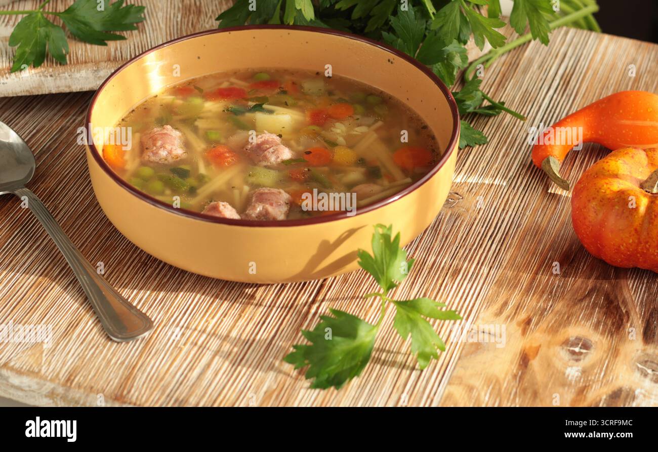 Minestrone tradizionale italiano con verdure, salsiccia e pasta, servito in una ciotola di argilla su tavola di legno. Cibo e stile di vita sano Foto Stock