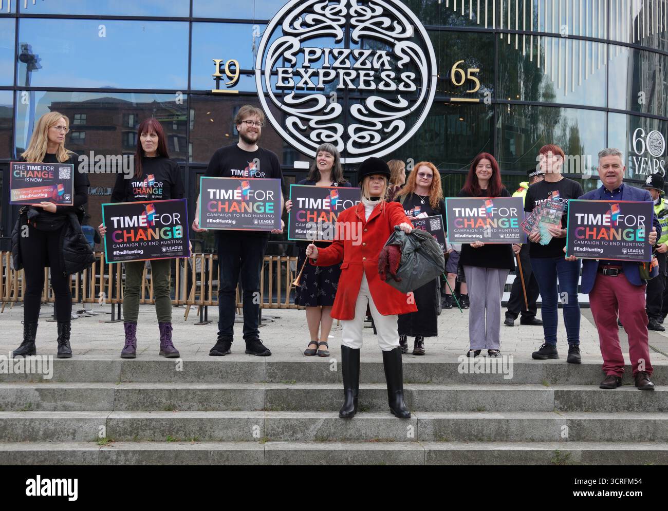 I manifestanti all'esterno del Pizza Express tengono dei cartelli che recitano "tempo per il cambiamento" in una campagna per terminare la caccia, con uno vestito da caccia tradizionale. Foto Stock