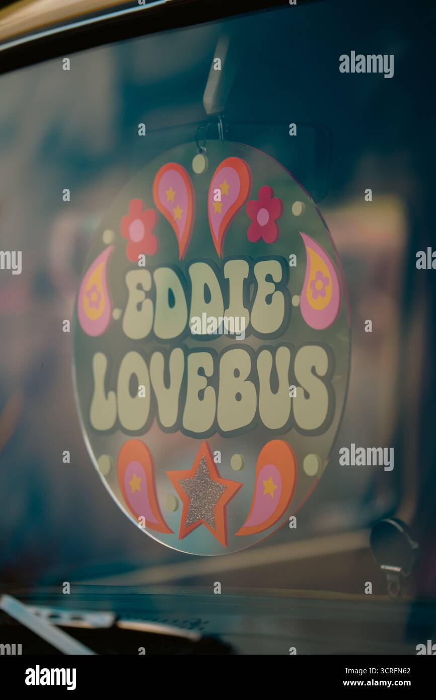 Londra, Regno Unito – 2025.09.27 – primo piano di un cartello retrò con la scritta “Eddie Lovebus” con fiori colorati e disegni paisley, appeso all'interno di una classica Volkswa Foto Stock