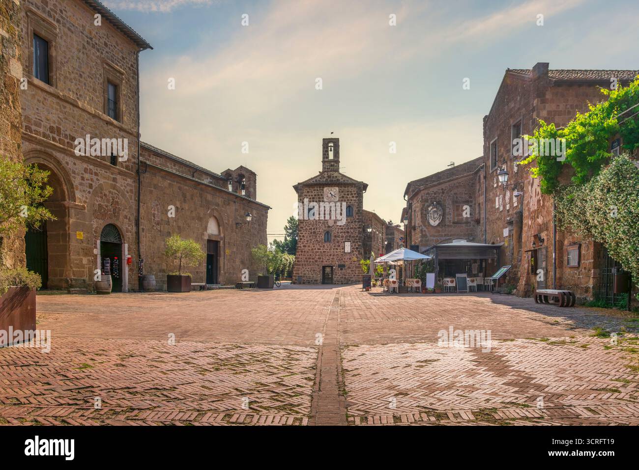 Storica piazza principale nel borgo medievale di Sovana con la torre dell'orologio del Palazzo dell'Archivio. Pavimentazione in mattoni nella città etrusca, Maremma, Toscana, Italia Foto Stock