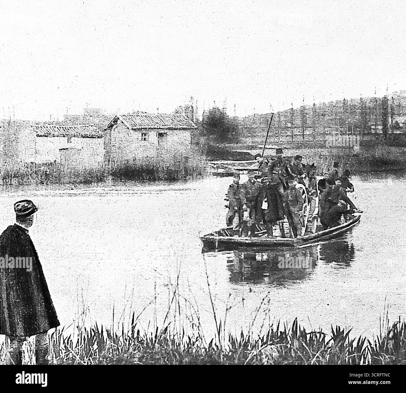 Le truppe francesi usano un vecchio traghetto di legno per attraversare un fiume durante la prima guerra mondiale, c.1915. Con i ponti distrutti, i metodi improvvisati permisero ai soldati e alle provviste di muoversi attraverso i corsi d'acqua. Pubblicata su le Miroir, questa immagine mette in evidenza il valore continuo delle tradizionali imbarcazioni fluviali in tempo di guerra, aiutando pattuglie e distaccamenti a raggiungere la riva opposta nonostante i danni dell'artiglieria. Foto Stock