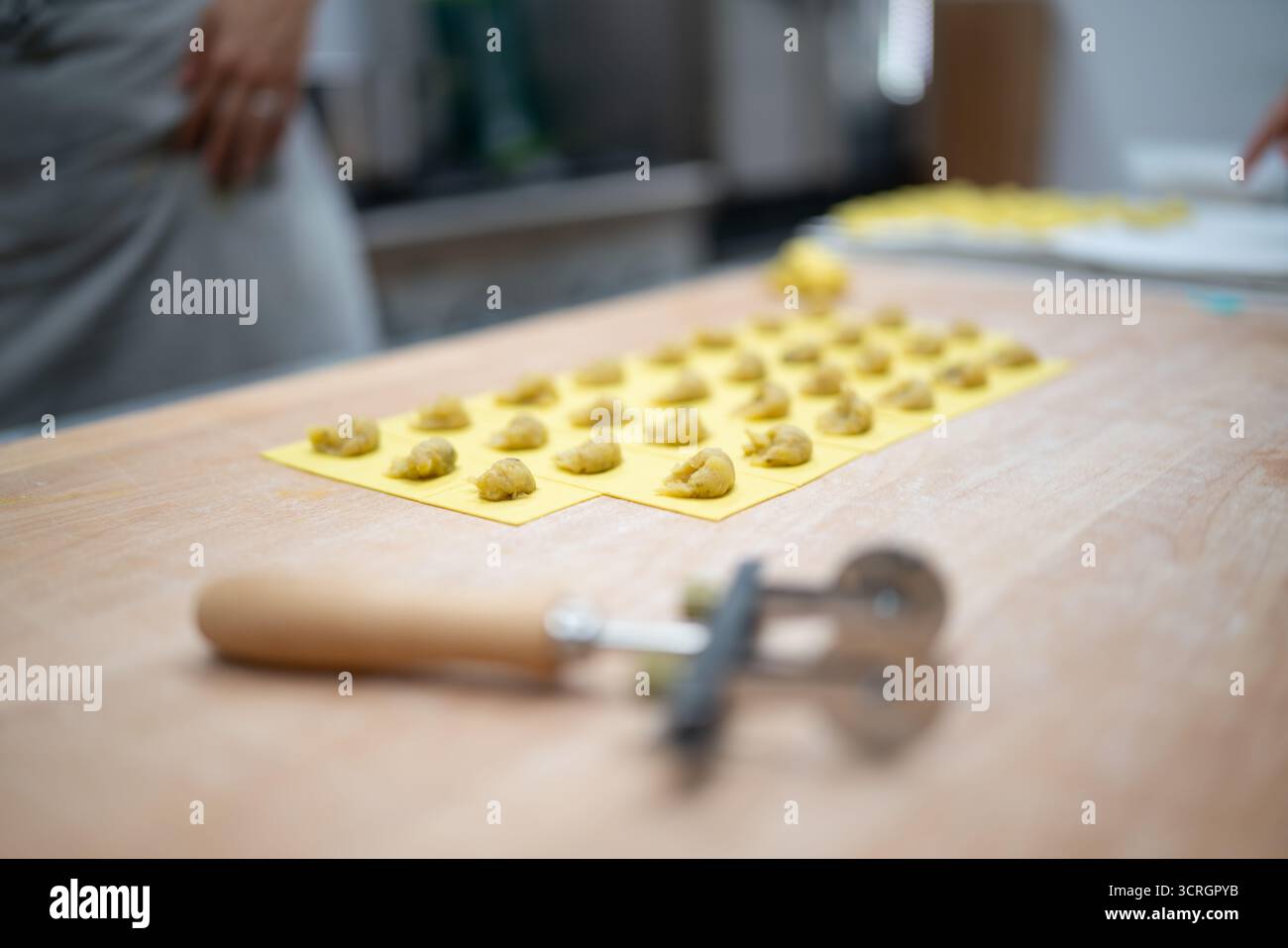 Pasta di ripieno fatta a mano con ravioli preparati con cura su una sagoma gialla pronta per la cottura Foto Stock