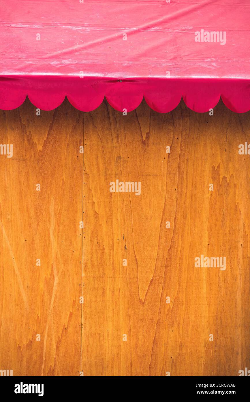 Una vivace tenda rosa fornisce ombra per una parete di legno in una vivace scena di mercato all'aperto Foto Stock