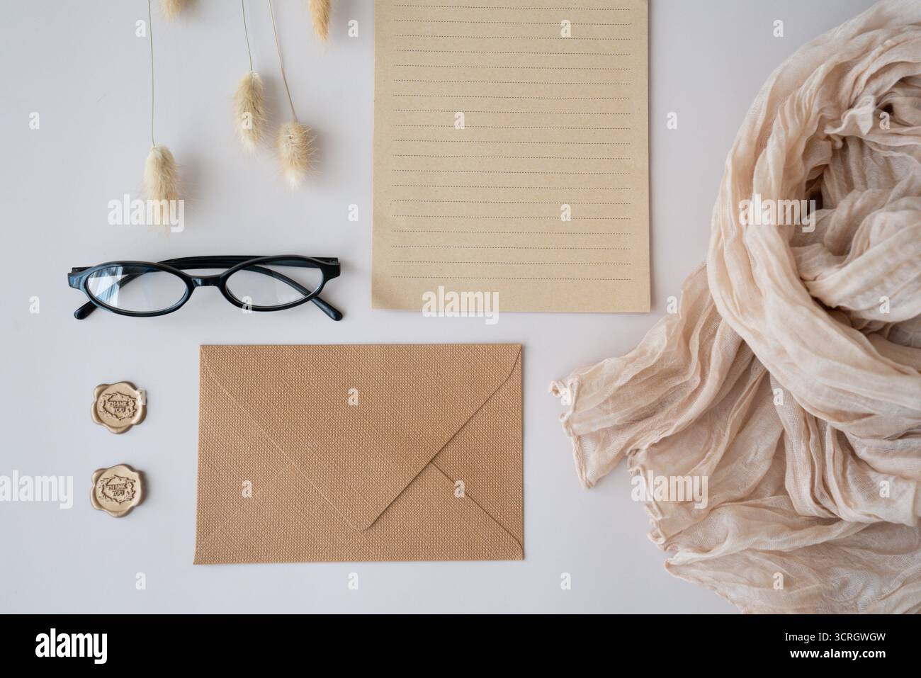 Area di lavoro con appunti, occhiali, buste artigianali, francobolli di ringraziamento e sciarpa su sfondo beige. Flat Lay, vista dall'alto, blog, sito Web, social media Foto Stock