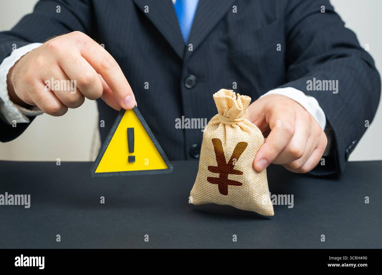 Un uomo con un segno di attenzione e un sacco di soldi in yen o yuan. Restrizioni, politica monetaria. Sanzioni, deficit di bilancio, fondo di emergenza. Utile per finan Foto Stock
