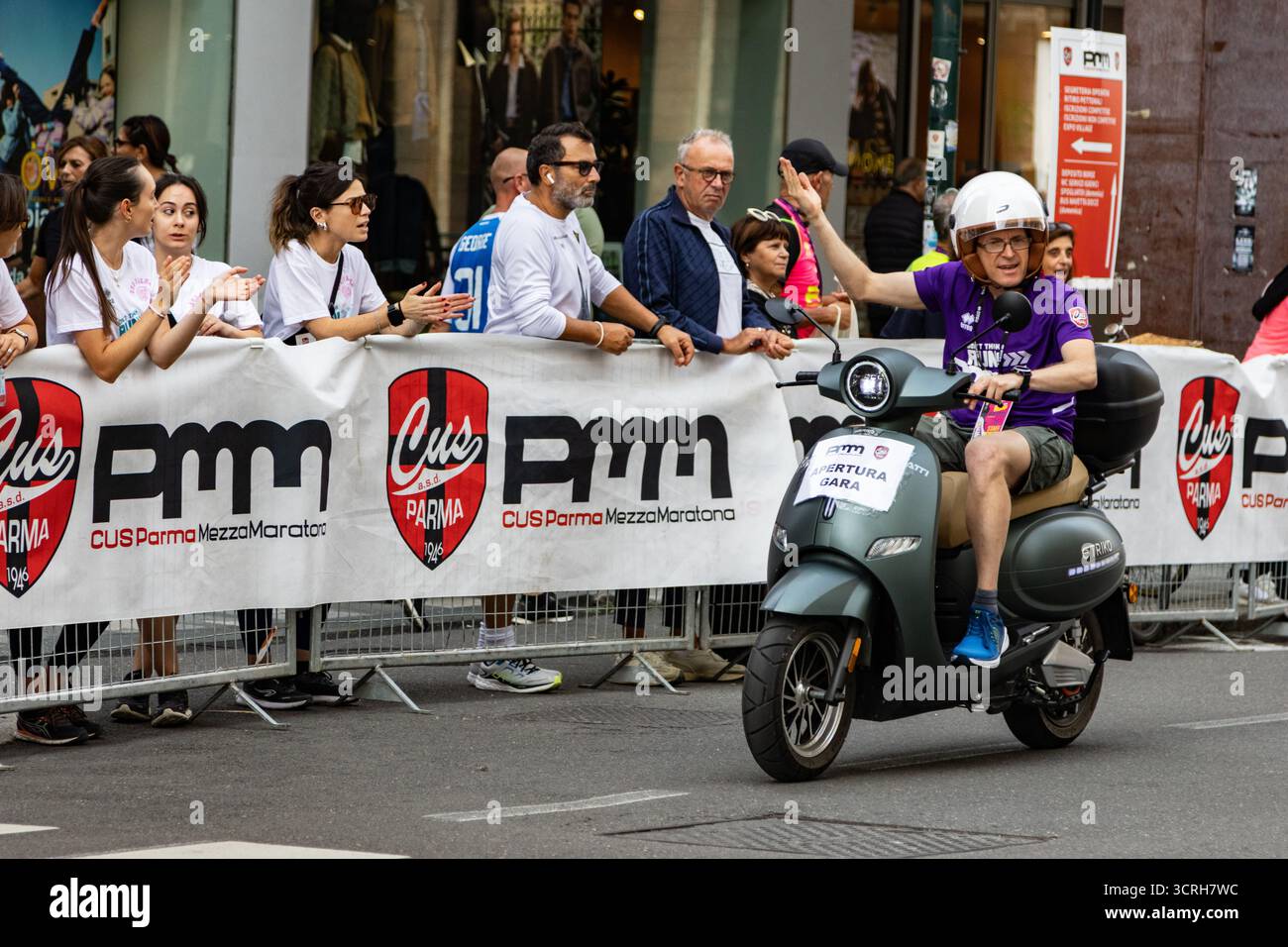 Uno scooter guida l'apertura della maratona, mentre gli spettatori entusiasti fanno il tifo per le strade della città, creando emozioni per l'evento sportivo competitivo Foto Stock