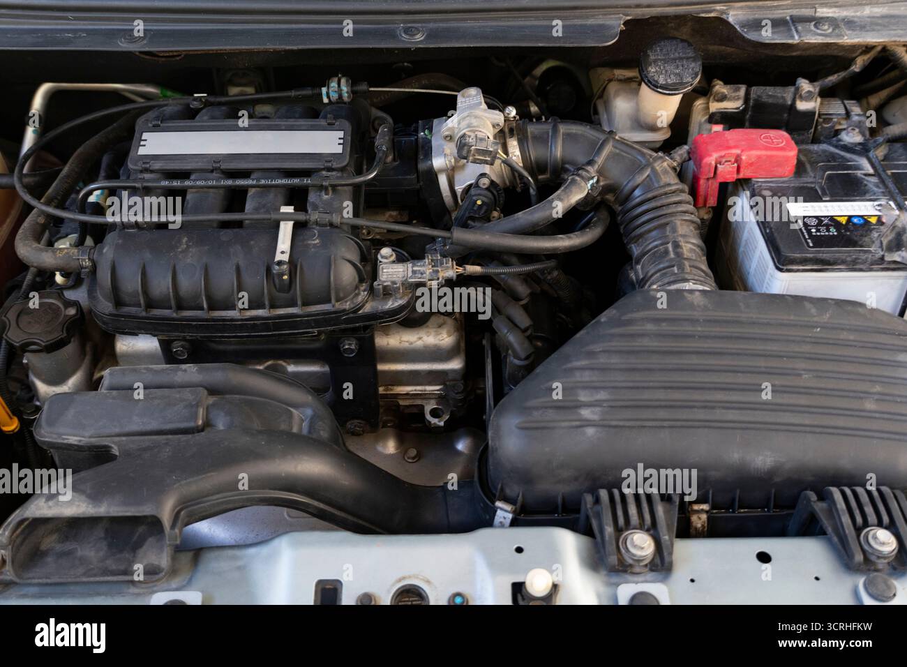 Foto in primo piano ad alta risoluzione di un motore di un'auto sotto il cofano. I componenti automobilistici, tra cui batteria, presa d'aria, corpo farfallato e cablaggio, sono puliti Foto Stock