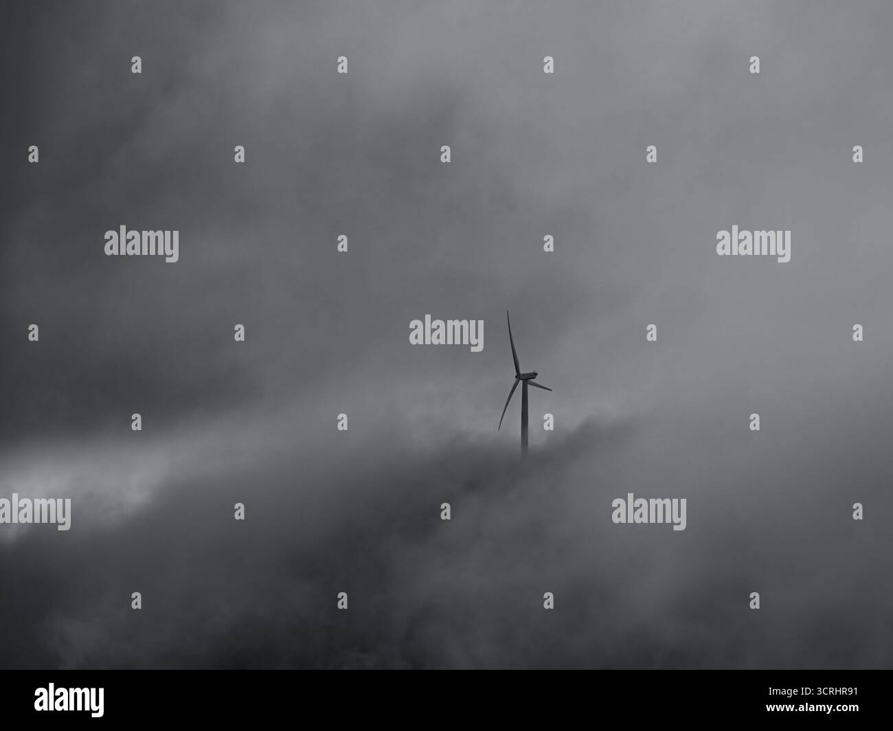 Turbine eoliche che emergono da nuvole nebbiose – scenario minimalista di energia rinnovabile che simboleggia la sostenibilità e l'energia pulita Foto Stock