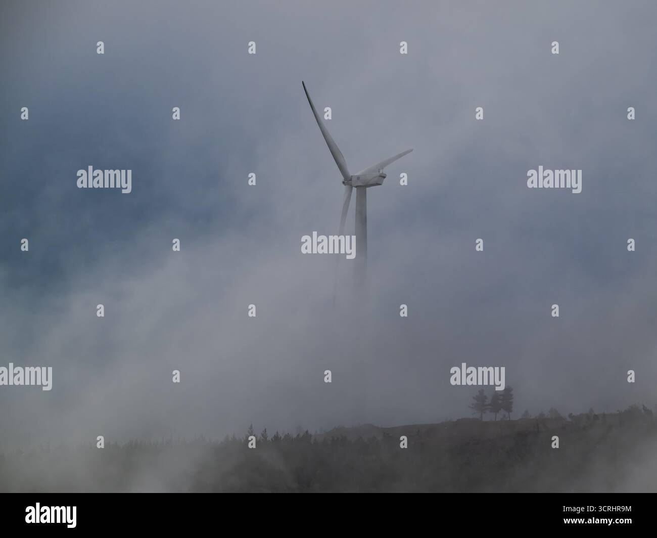 Turbine eoliche che emergono da nuvole nebbiose – scenario minimalista di energia rinnovabile che simboleggia la sostenibilità e l'energia pulita Foto Stock