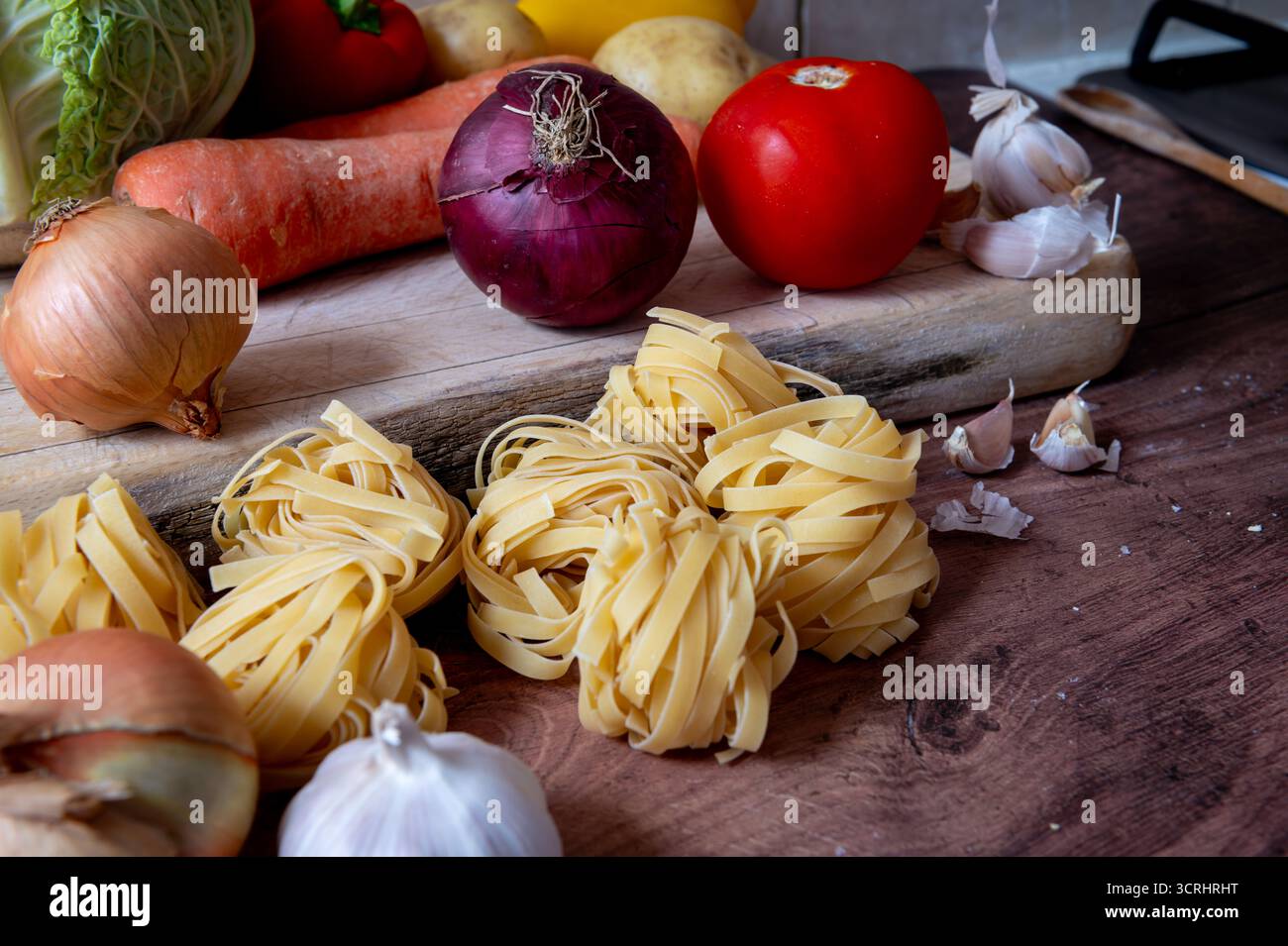Asciugare la pasta italiana tagliatelle su un piano di lavoro della cucina insieme a varie verdure. Foto Stock