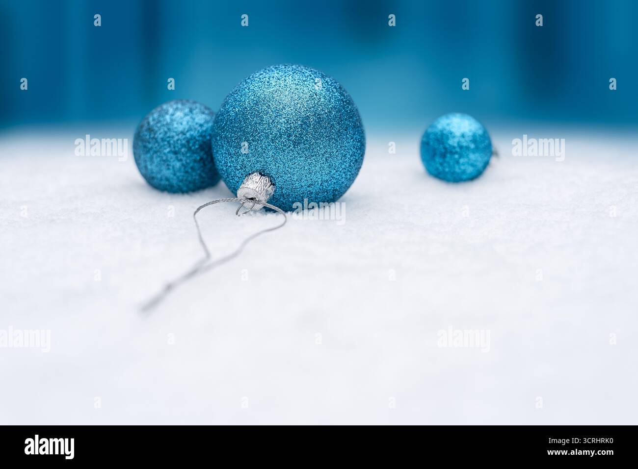 Blu Natale baule sulla neve su sfondo blu brillante festivo con spazio copia per il design natalizio Foto Stock