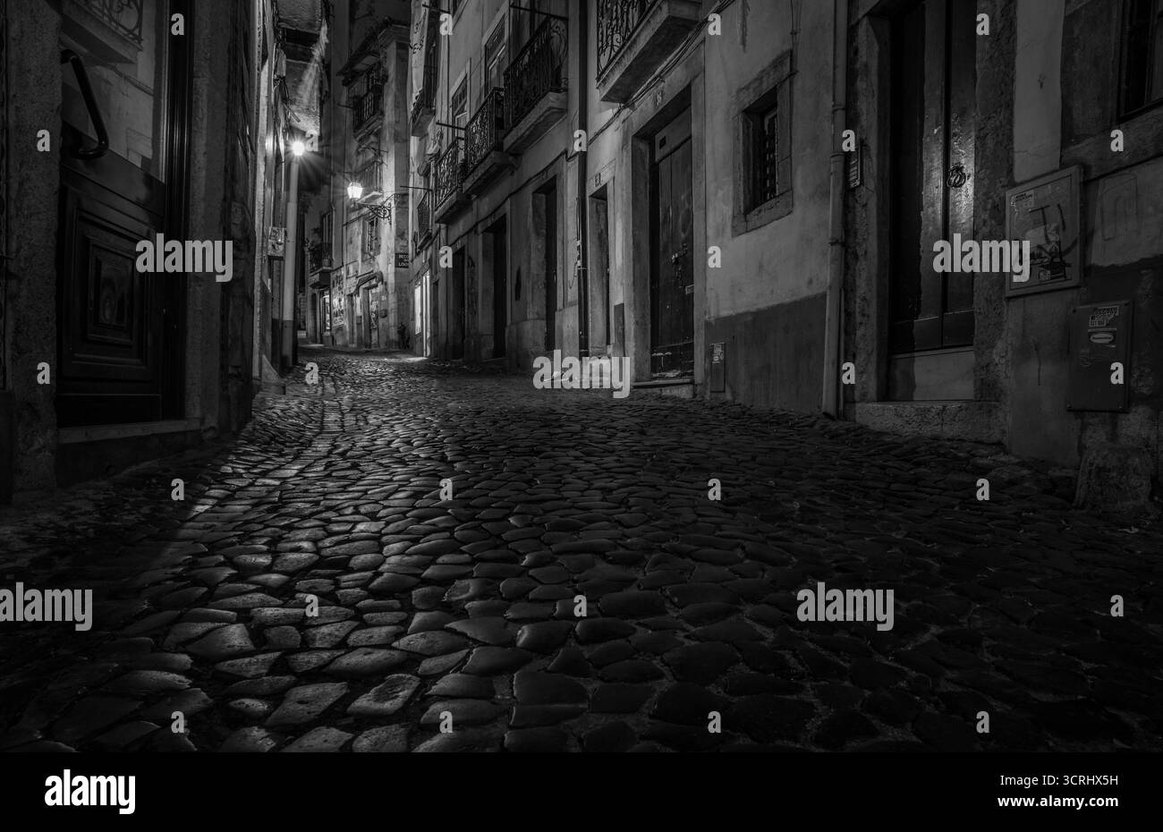Vecchia strada acciottolata di notte con case d'epoca e lampioni nella storica città europea, atmosfera bianca e nera Foto Stock