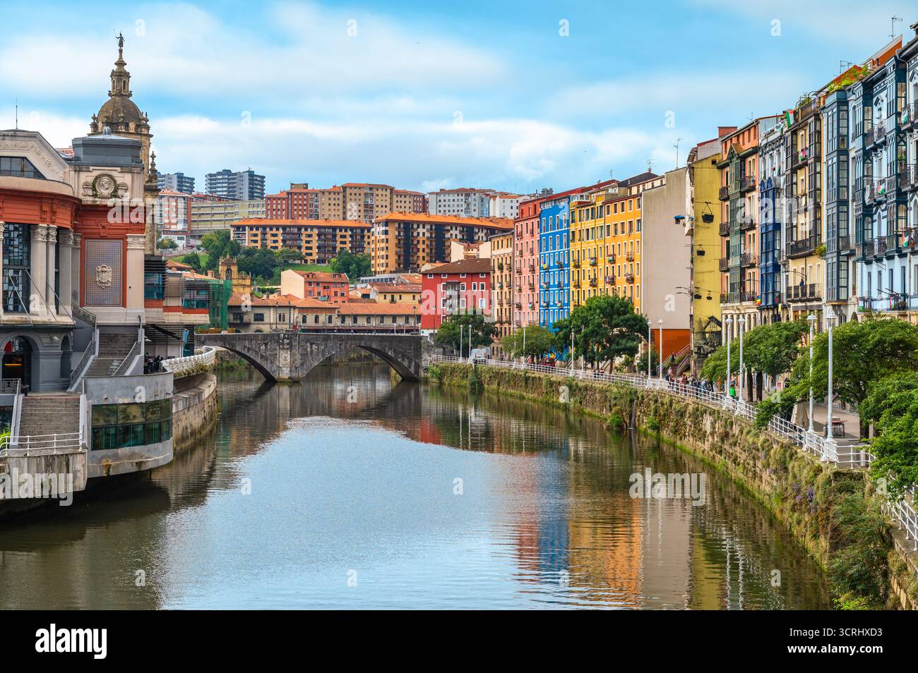 Foto di viaggio del colorato lungomare di Bilbao, Spagna, con il mercato di Ribera, le riflessioni sul fiume e il ponte Foto Stock