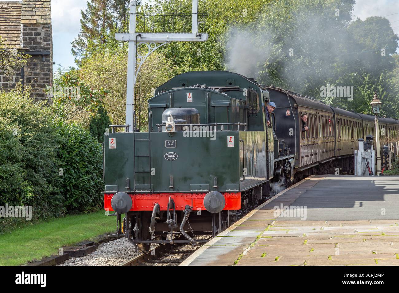 Un treno a vapore (locomotiva) in retromarcia che porta carrozze nella stazione di Oakworth sulla Keighley and Worth Valley Railway Line nello Yorkshire. Foto Stock