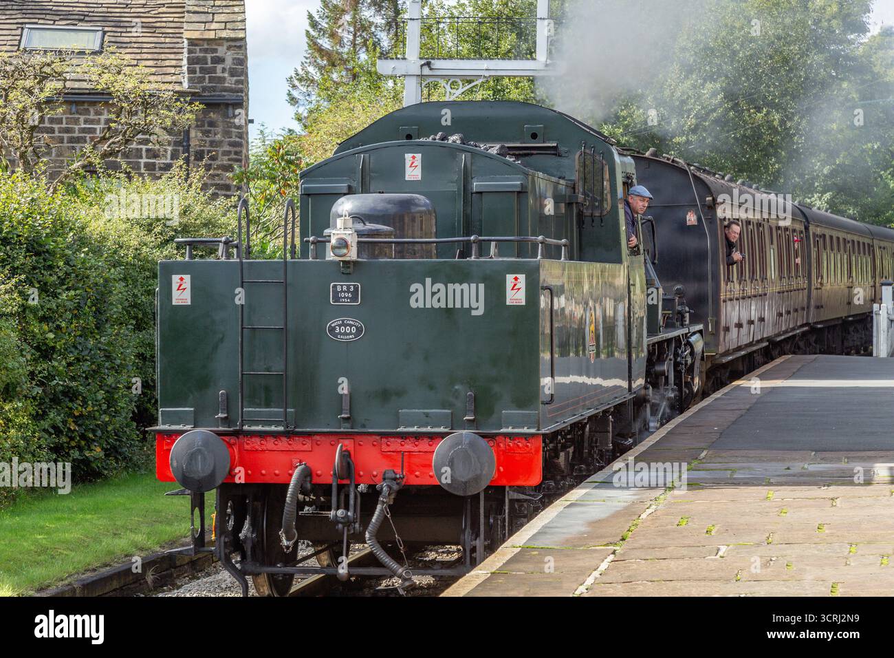Un treno a vapore (locomotiva) in retromarcia che porta carrozze nella stazione di Oakworth sulla Keighley and Worth Valley Railway Line nello Yorkshire. Foto Stock
