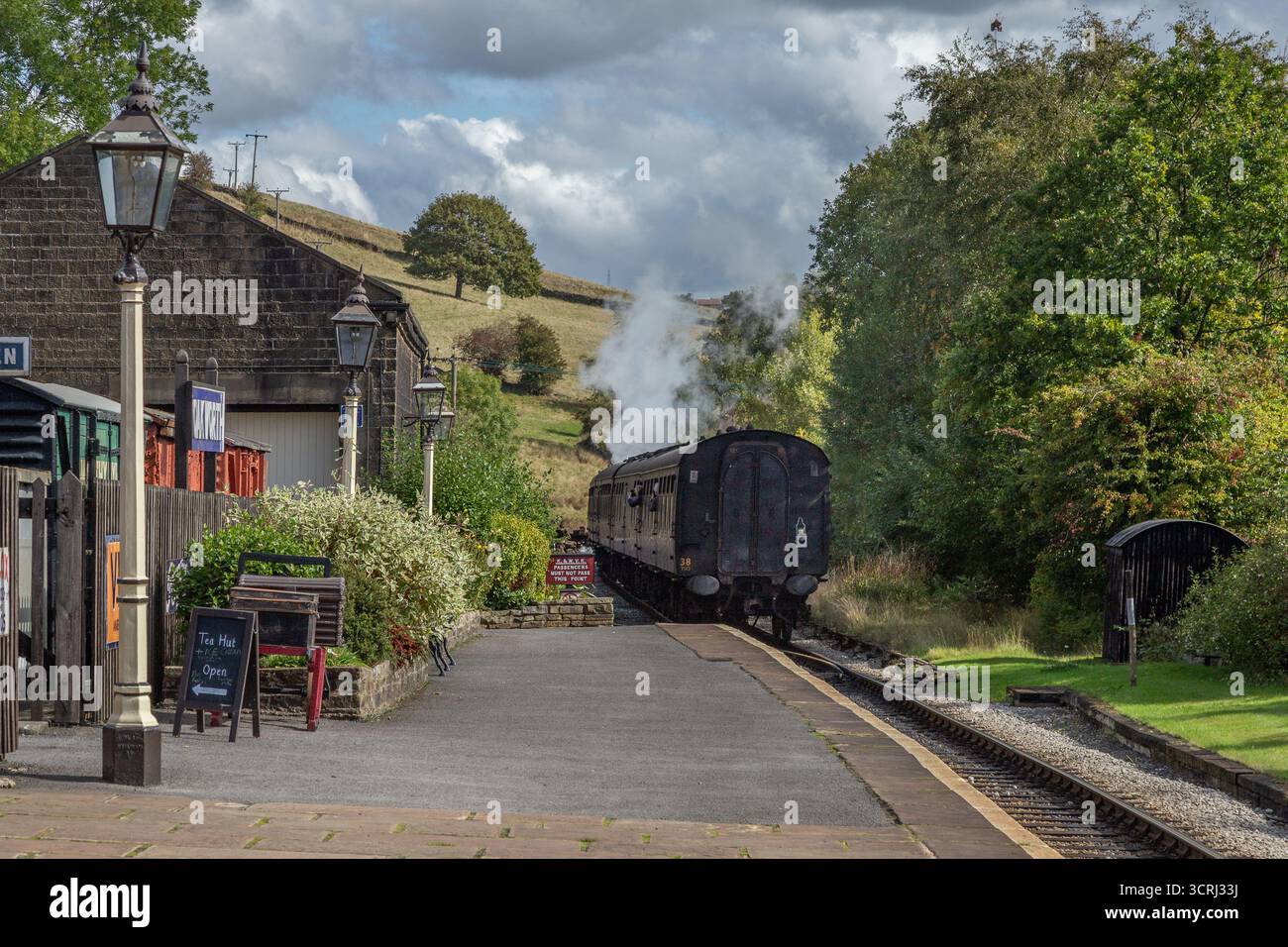 Un treno a vapore che parte dalla stazione ferroviaria di Oakworth, nello Yorkshire, una delle location per i film "Railway Children". Keighley and Worth Valley Railway. Foto Stock