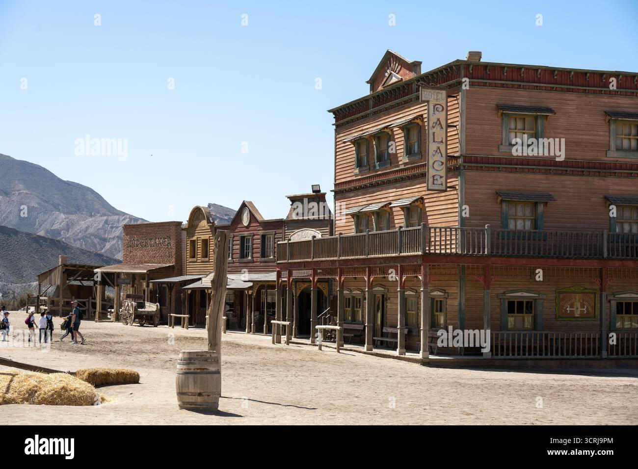 Una città in stile occidentale con edifici in legno, un saloon chiamato 'Palace' e una strada polverosa, adagiata su uno sfondo montuoso Foto Stock