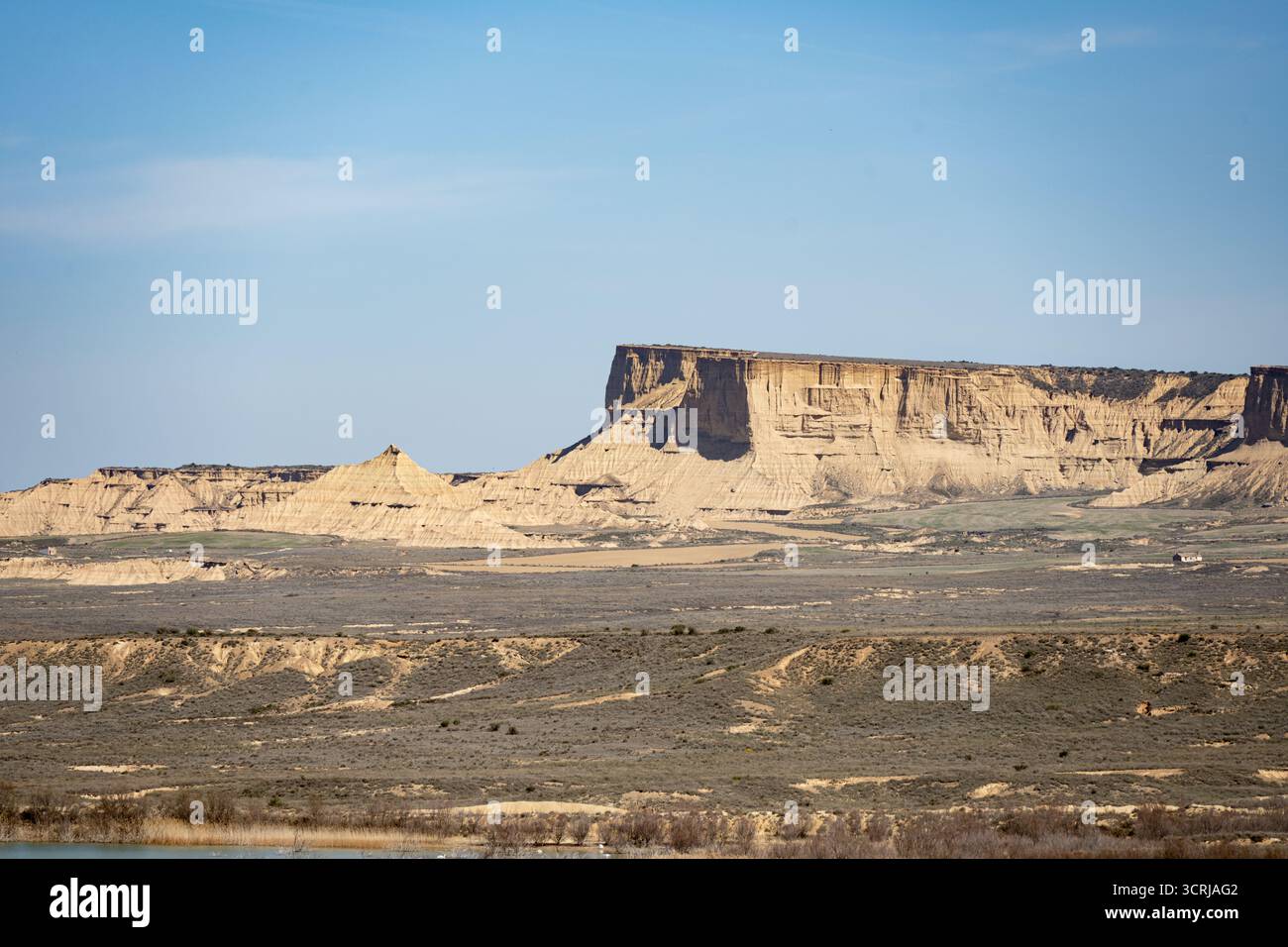 Paesaggio arido con formazioni di arenaria erose sotto un cielo azzurro dalle Bardenas Reales, Spagna Foto Stock
