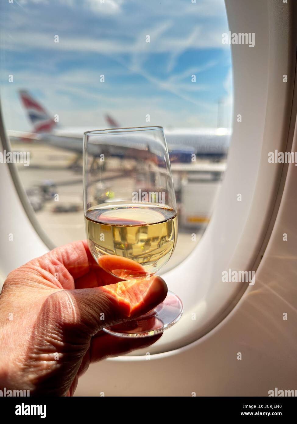 Londra, Inghilterra, Regno Unito - 19 maggio 2025: Persona che tiene un bicchiere di champagne nella cabina business class Club World di un aereo della British Airways. - Immagine stock catturata con smartphone
