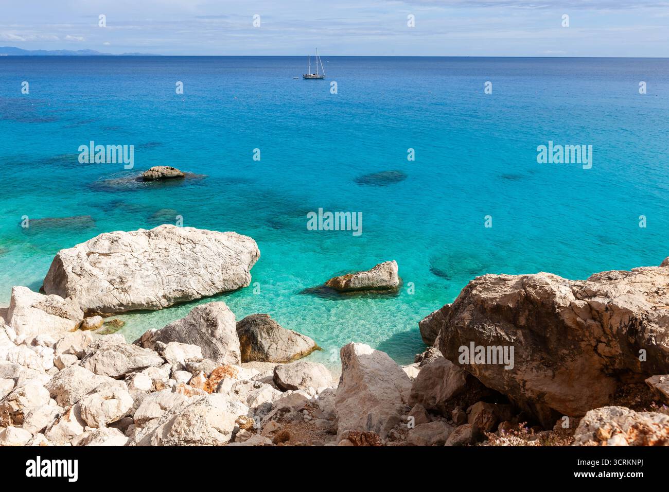 Sardegna, Italia. Mare Mediterraneo cristallino, incredibili acque turchesi color smeraldo, splendide rocce e una barca a vela bianca. Foto Stock