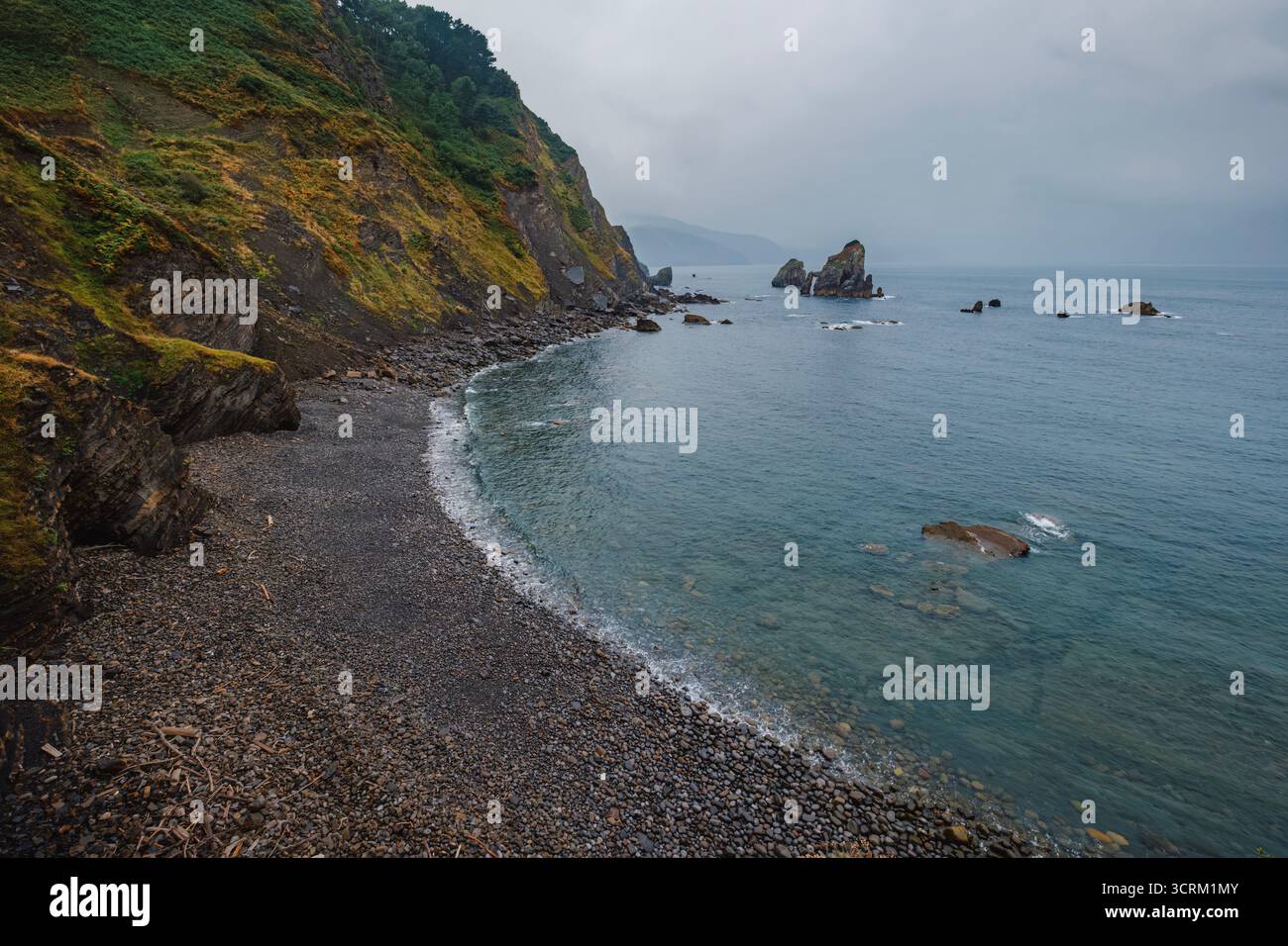 Aspra Pebble Beach tra San Juan de Gaztelugatxe, Paesi Baschi, Spagna. Green Cliffs, formazioni rocciose, costa atlantica, Remote Bay, scenario costiero Foto Stock