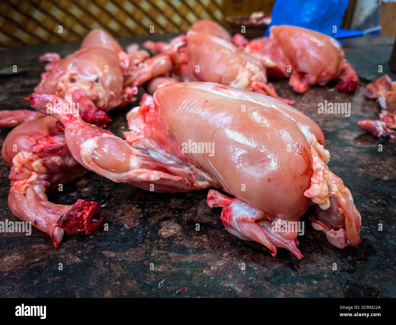 Parti di pollo crude esposte sul tavolo di un macellaio, che mostrano carne fresca di pollame in un ambiente di mercato Foto Stock