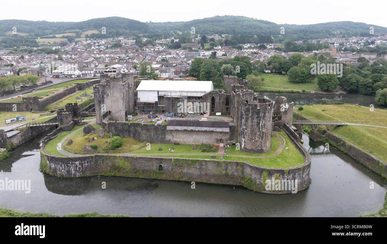Vista aerea dell'imponente castello di Caerphilly, le sue mura di pietra intemprate abbracciate da un fossato sereno che riflette il cielo coperto, una testimonianza di secoli di storia, Caerphilly, Galles, Regno Unito. Foto Stock