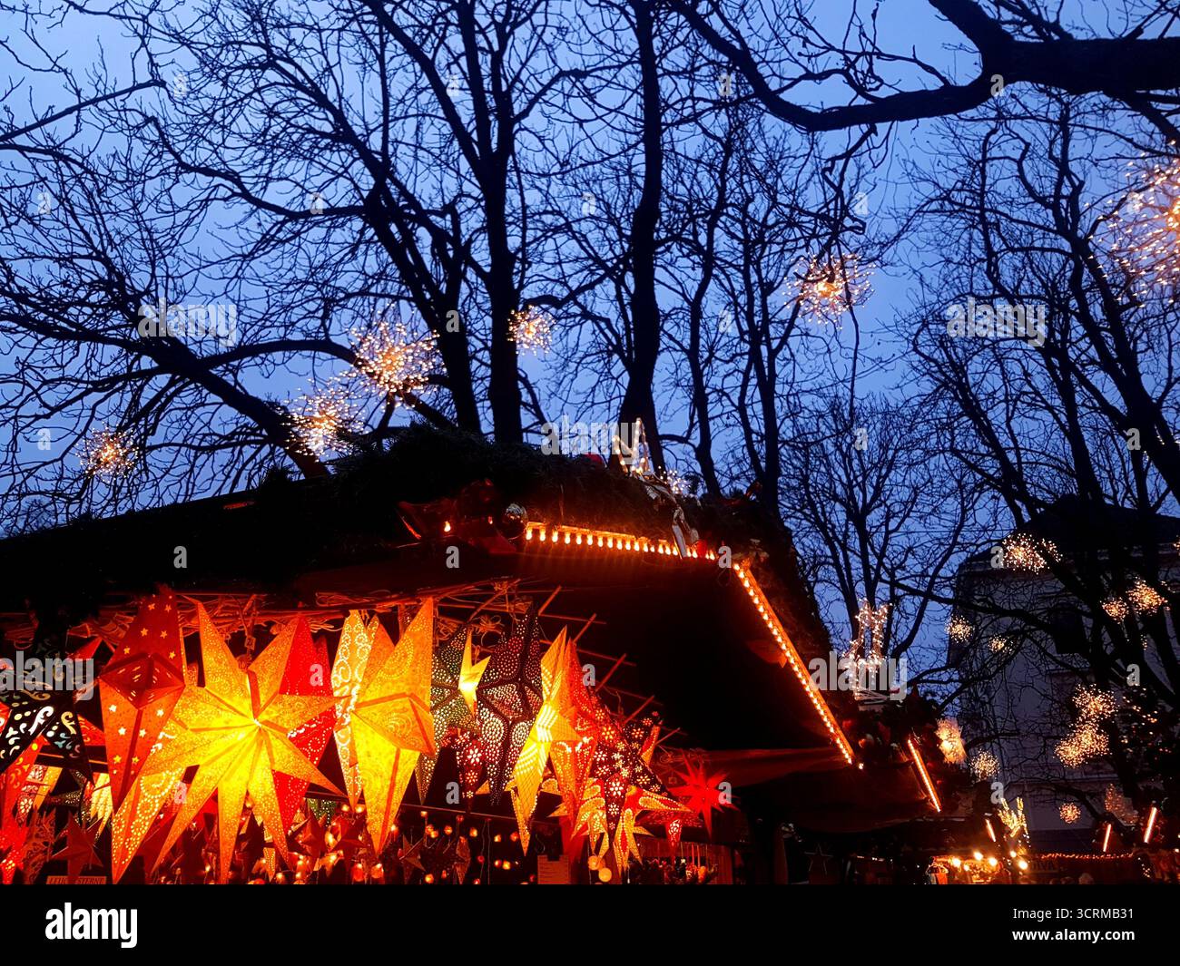 Un mercatino natalizio a Basilea, in Svizzera, si illumina con calore alla luce della sera. Gli alberi sono adornati da innumerevoli stelle splendenti. Foto Stock