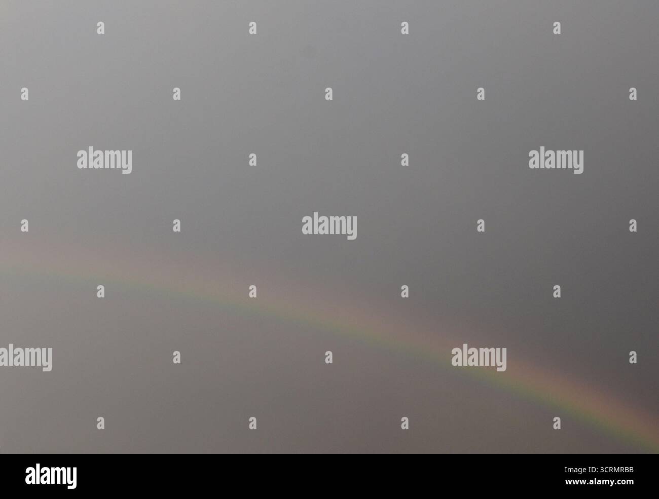 La natura dipinge un arcobaleno vivido su nuvole a strati, mescolando sensazionali tonalità del cielo con una luce eterea soffusa. Foto Stock