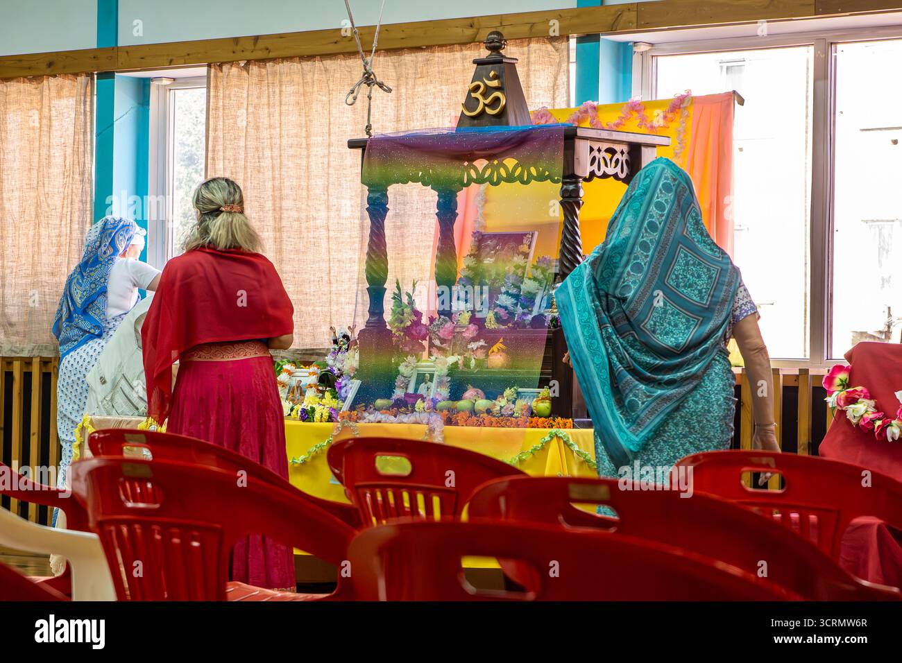 Russia - 10 settembre 2003. Spazio rituale interno con altare decorato con emblema Om, ritratti incorniciati, offerte di frutta. partecipanti al tradizionale Foto Stock