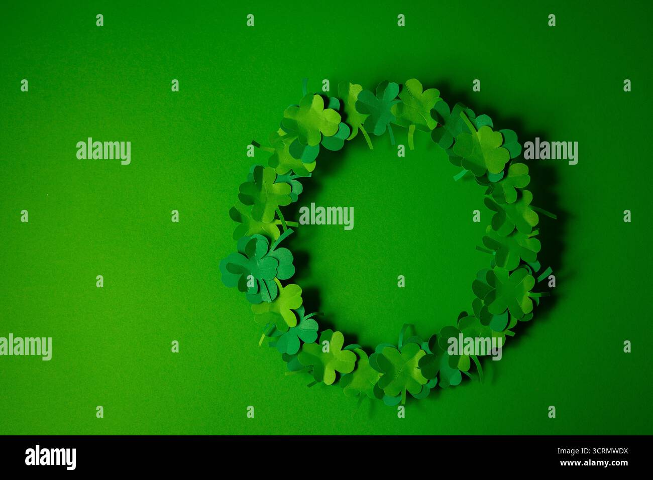 Ghirlanda di carta verde su sfondo verde. Concetto del giorno di San Patrizio. Foto Stock