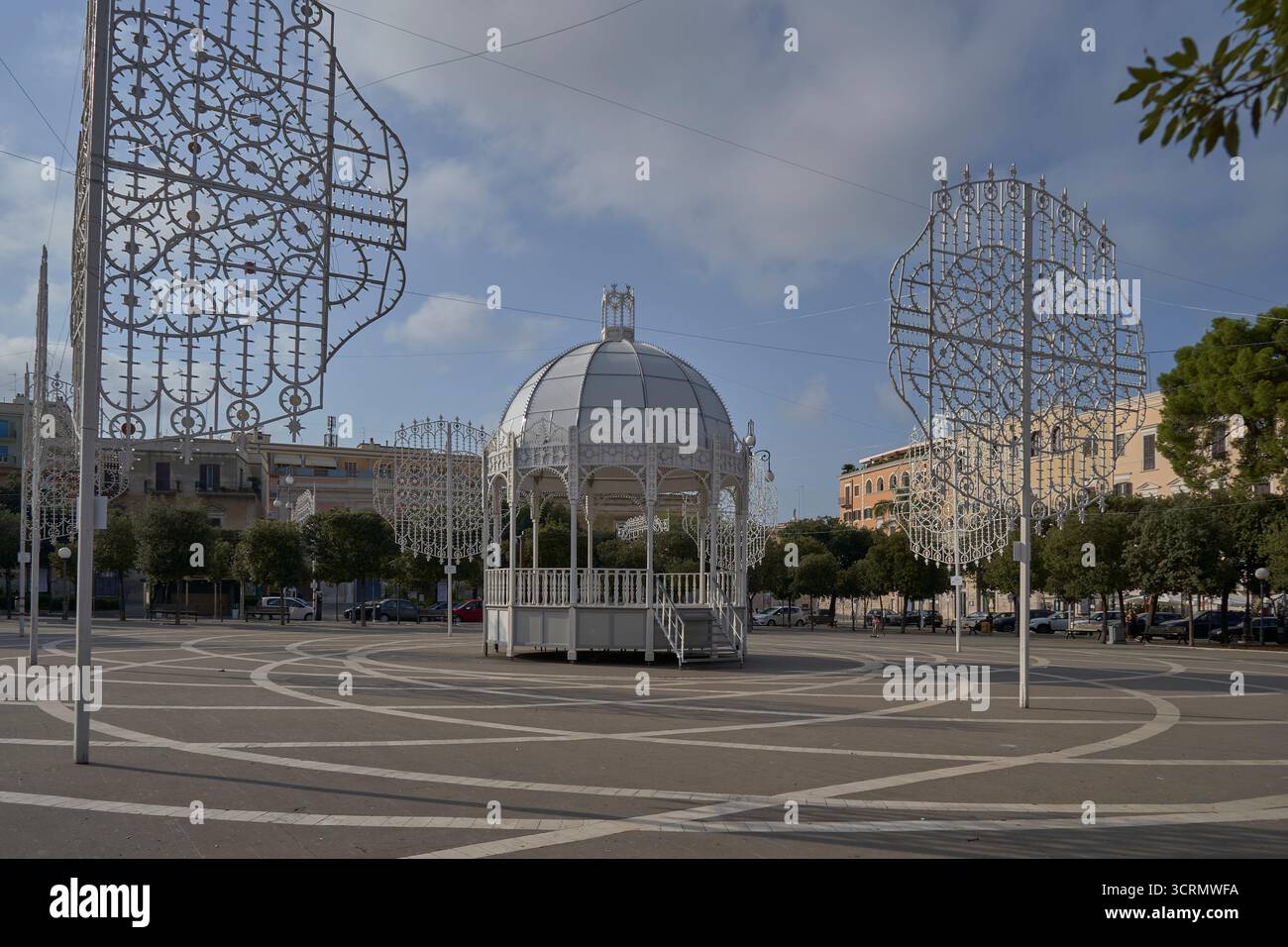 Elegante gazebo bianco con cupola in piazza urbana, incorniciato da strutture decorative luminose, giorno di sole con cielo blu Foto Stock