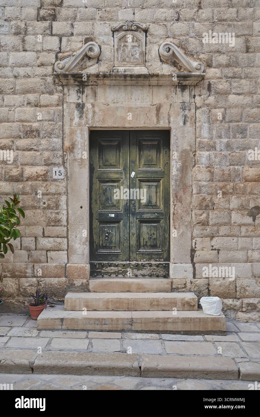 Porta in legno verde con struttura in pietra e dettagli incrociati, sfondo storico dell'architettura stradale europea Foto Stock