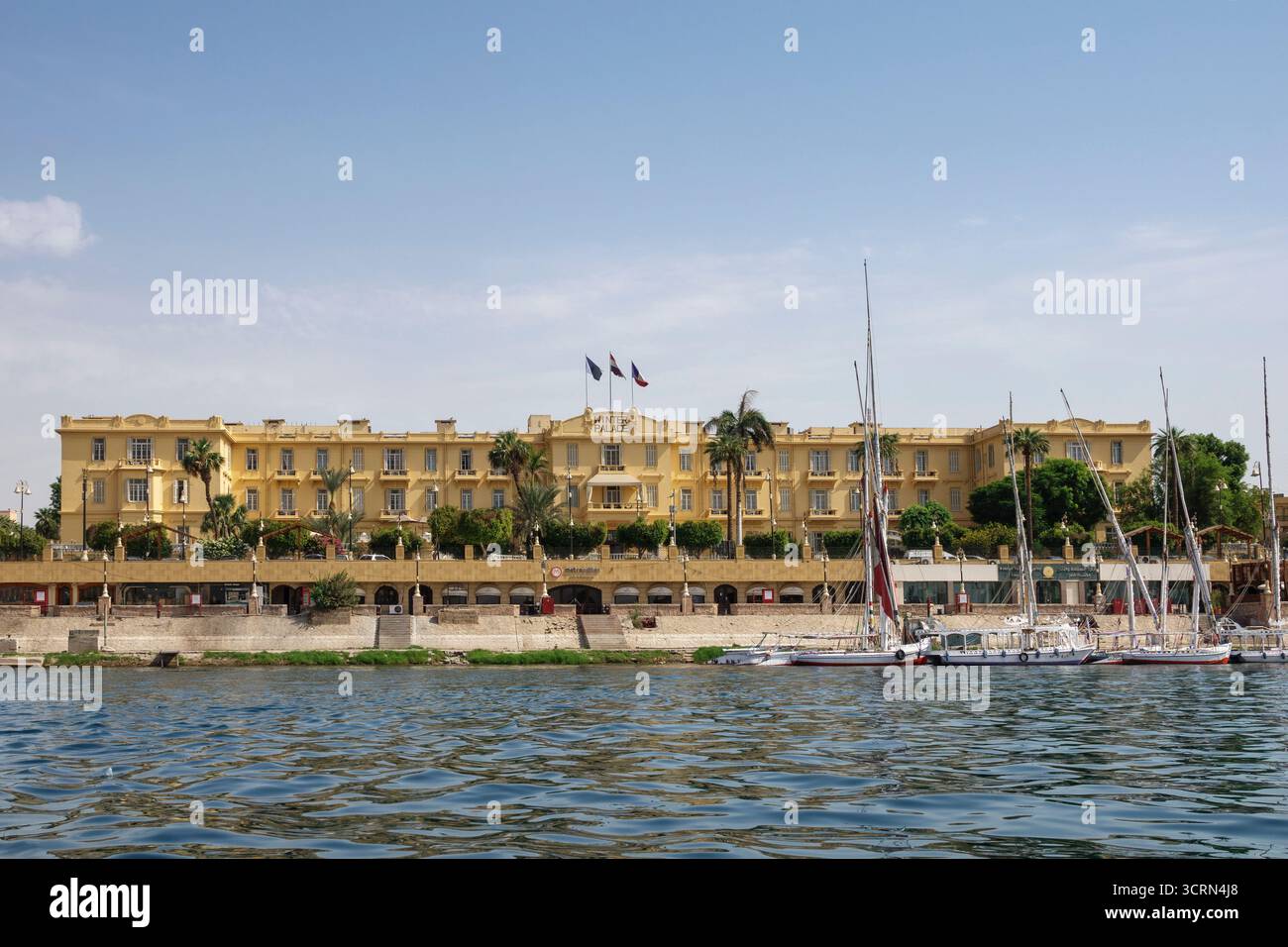 La facciata anteriore del Winter Palace Hotel sulle rive del Nilo, con le feluche ormeggiate di fronte, Luxor, Egitto Foto Stock