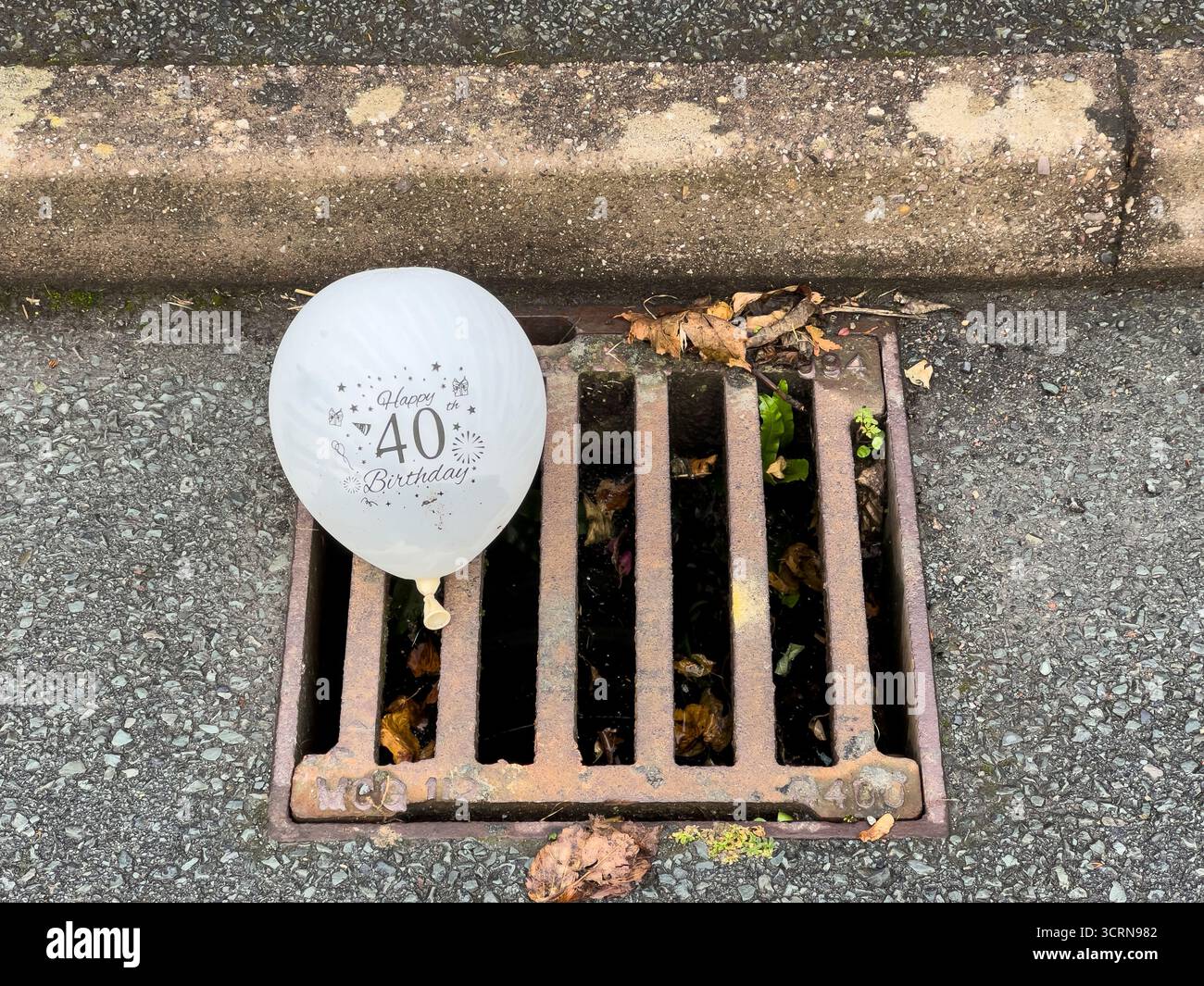 Un palloncino per la festa del 40° compleanno gettato in uno scarico dopo la festa (Regno Unito) Foto Stock