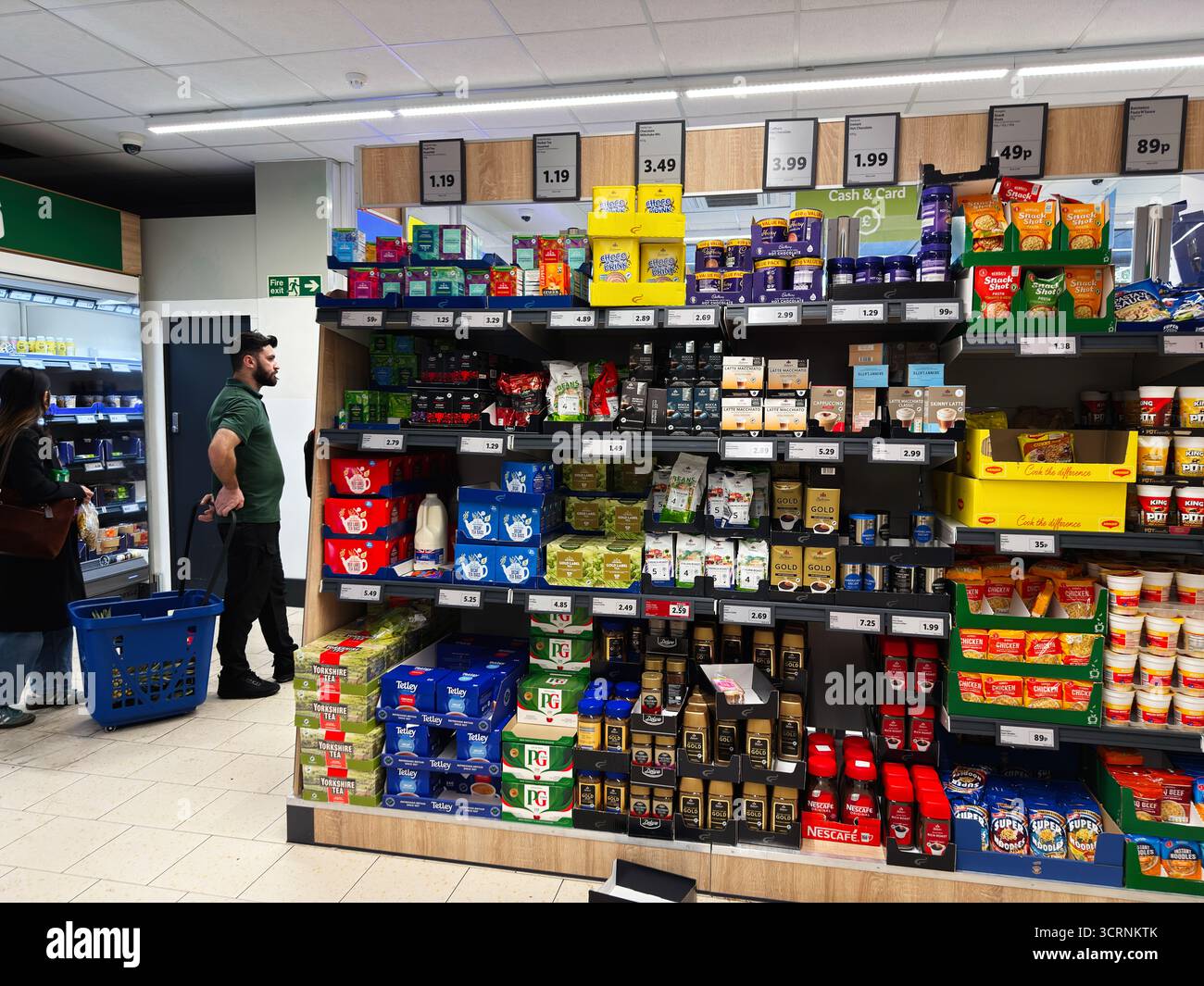 Manchester, Regno Unito - 25 settembre 2025: Affollato corridoio del negozio British Lidl con vari generi alimentari, spuntini, tè e caffè su scaffali ben riforniti. Foto Stock