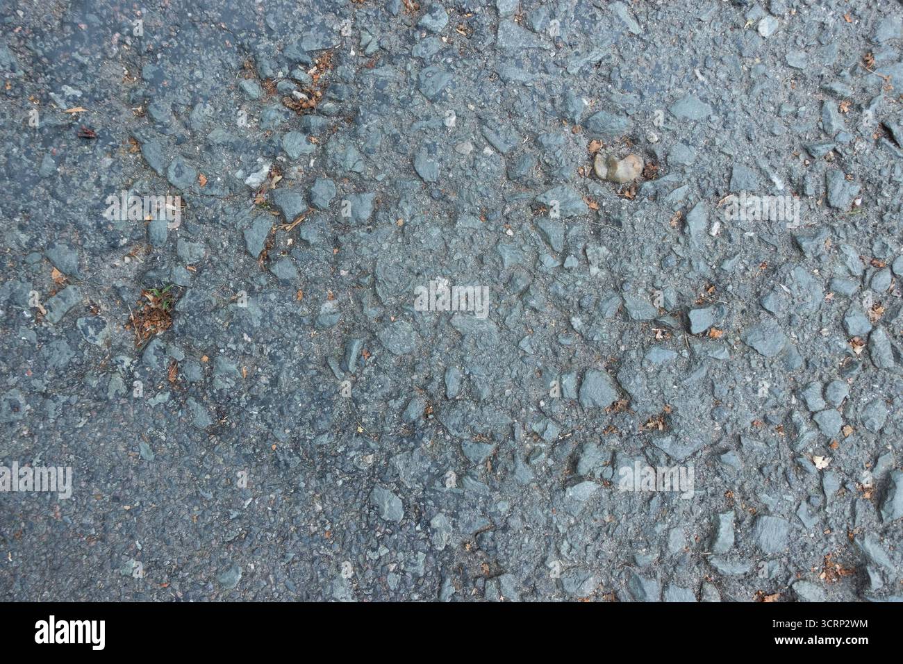 Primo piano della consistenza del terreno asfalto con pietre ruvide e piccoli detriti, fondo stradale urbano Foto Stock
