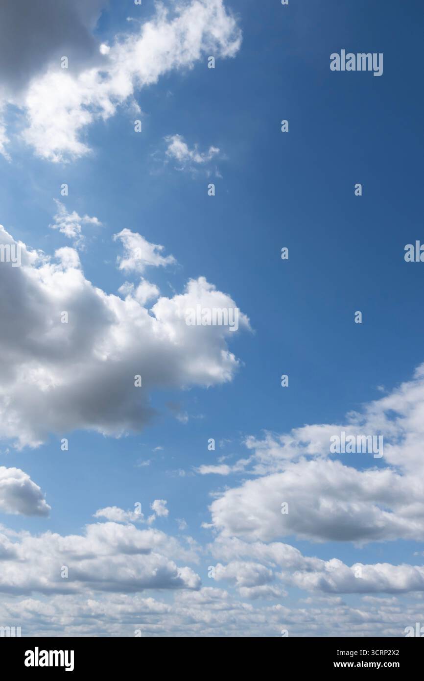 Cielo azzurro con nuvole bianche sparse in una giornata di sole brillante, sfondo dall'atmosfera limpida Foto Stock