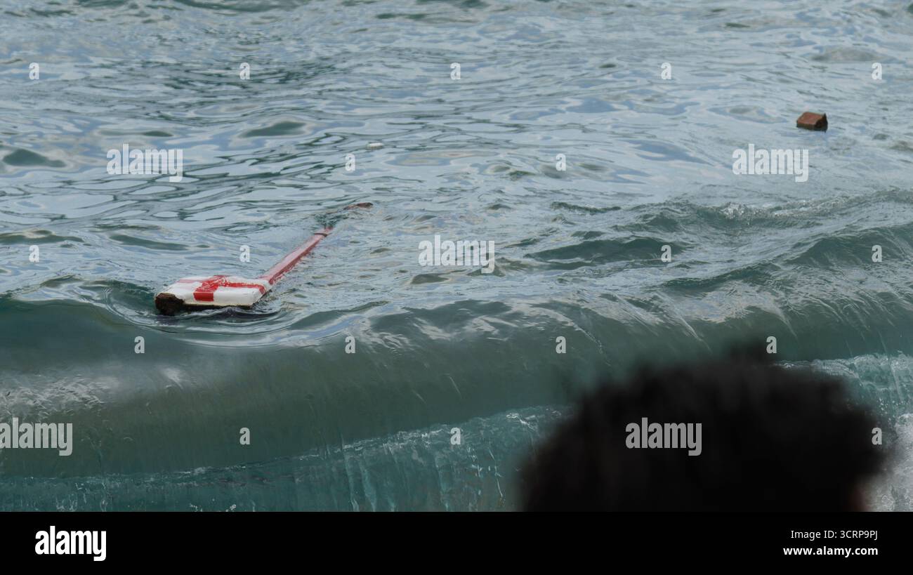 Un dispositivo galleggiante vitale può essere visto rimbalzare energicamente tra le onde, mostrando misure di sicurezza costiere Foto Stock