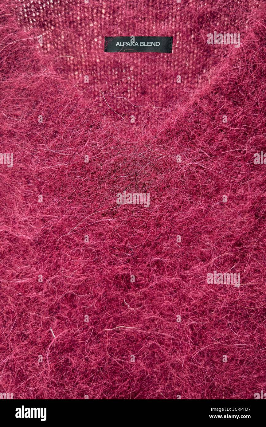Pullover con scollo a V Borgogna brillante con etichetta che identifica la miscela di alpaca in inglese. La superficie è soffice con fibre lunghe, caratteristica di Alpac Foto Stock