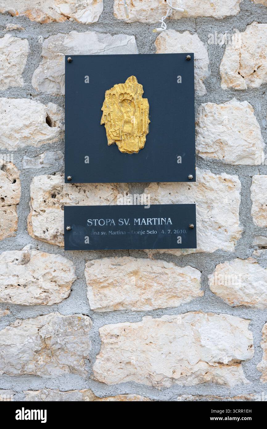 Una placca con emblemi color oro montata su un muro di pietra grezza con un cartello scuro sotto il piede di Reading St. Martin. La scena fonde tradizione e architettura Foto Stock