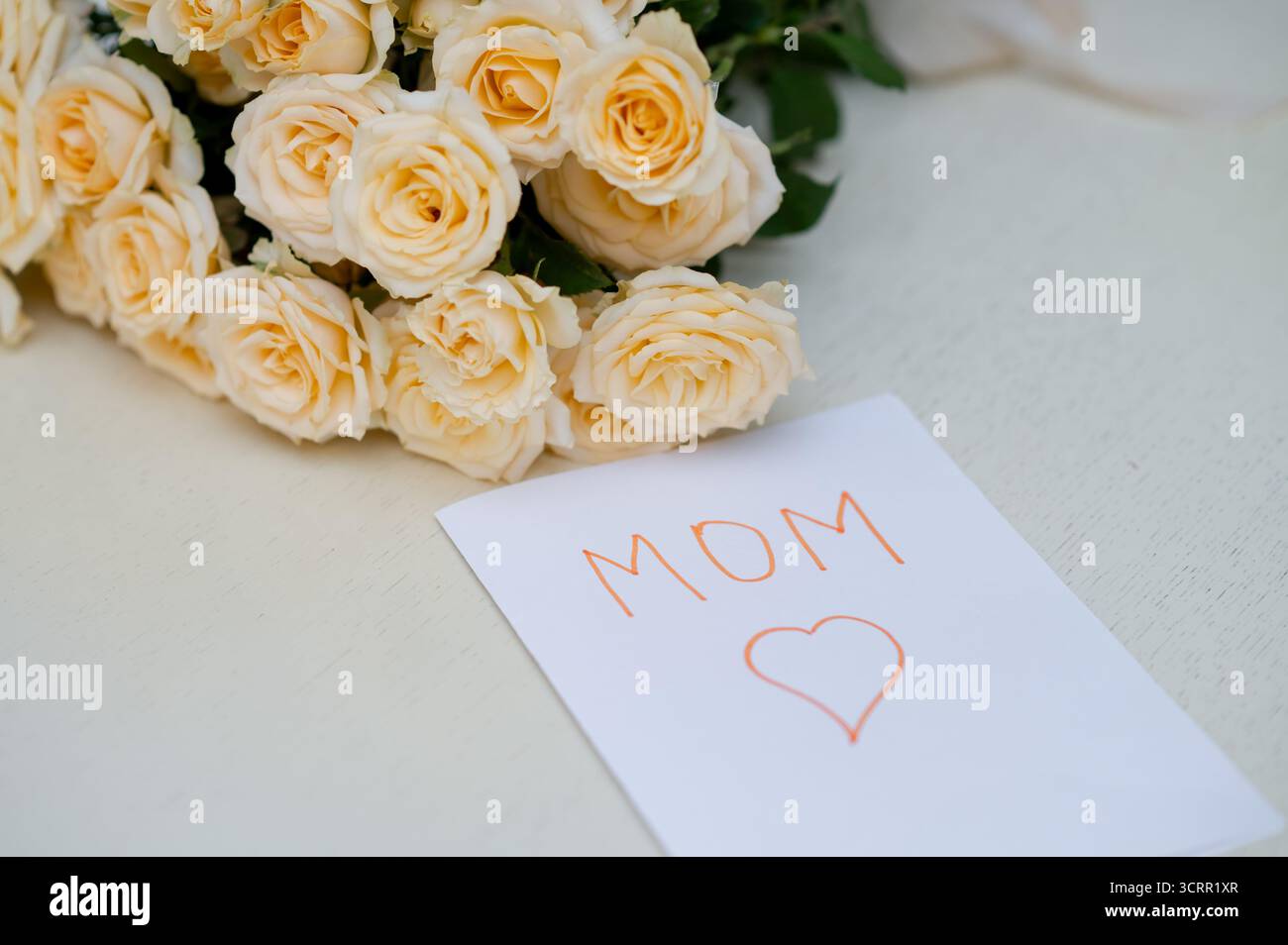 Biglietto d'auguri per bambini fatto a mano per la festa della mamma con un bouquet di rose gialle fresche, che simboleggia l'amore, la famiglia e la celebrazione della maternità Foto Stock