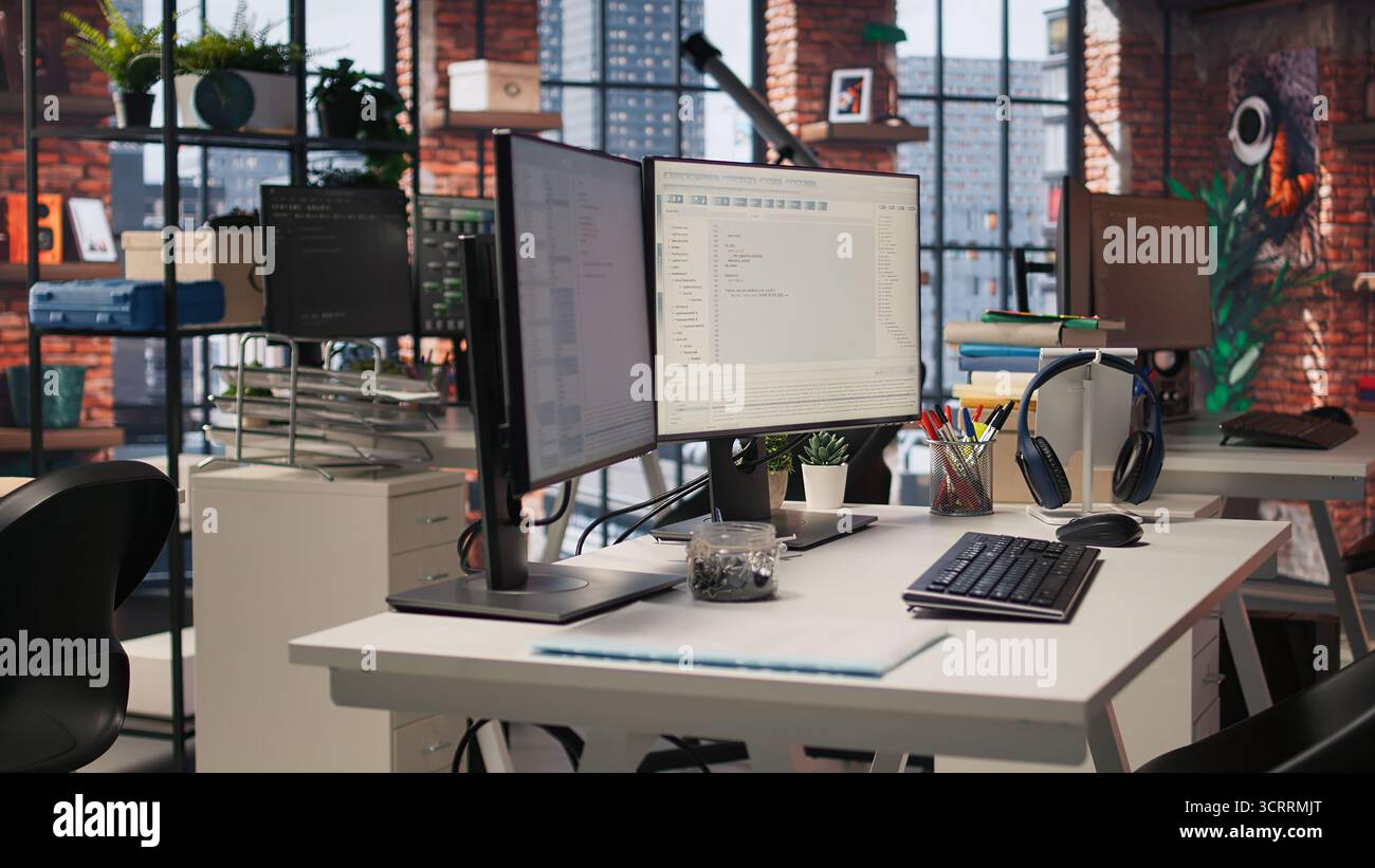 Schermi PC in un innovativo ufficio di avvio che mostrano i linguaggi di programmazione utilizzati per creare applicazioni. Agenzia di sviluppo software vuota utilizzata per ottimizzare il codice sui computer, ripresa da fotocamera portatile Foto Stock