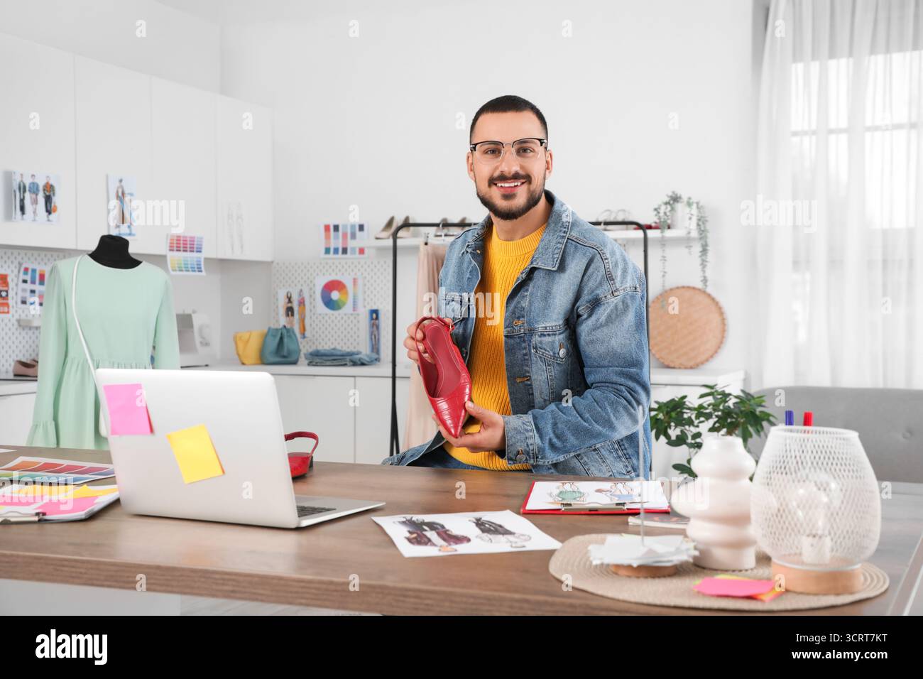Stilista maschile con video chat su laptop e tacchi alti in studio Foto Stock